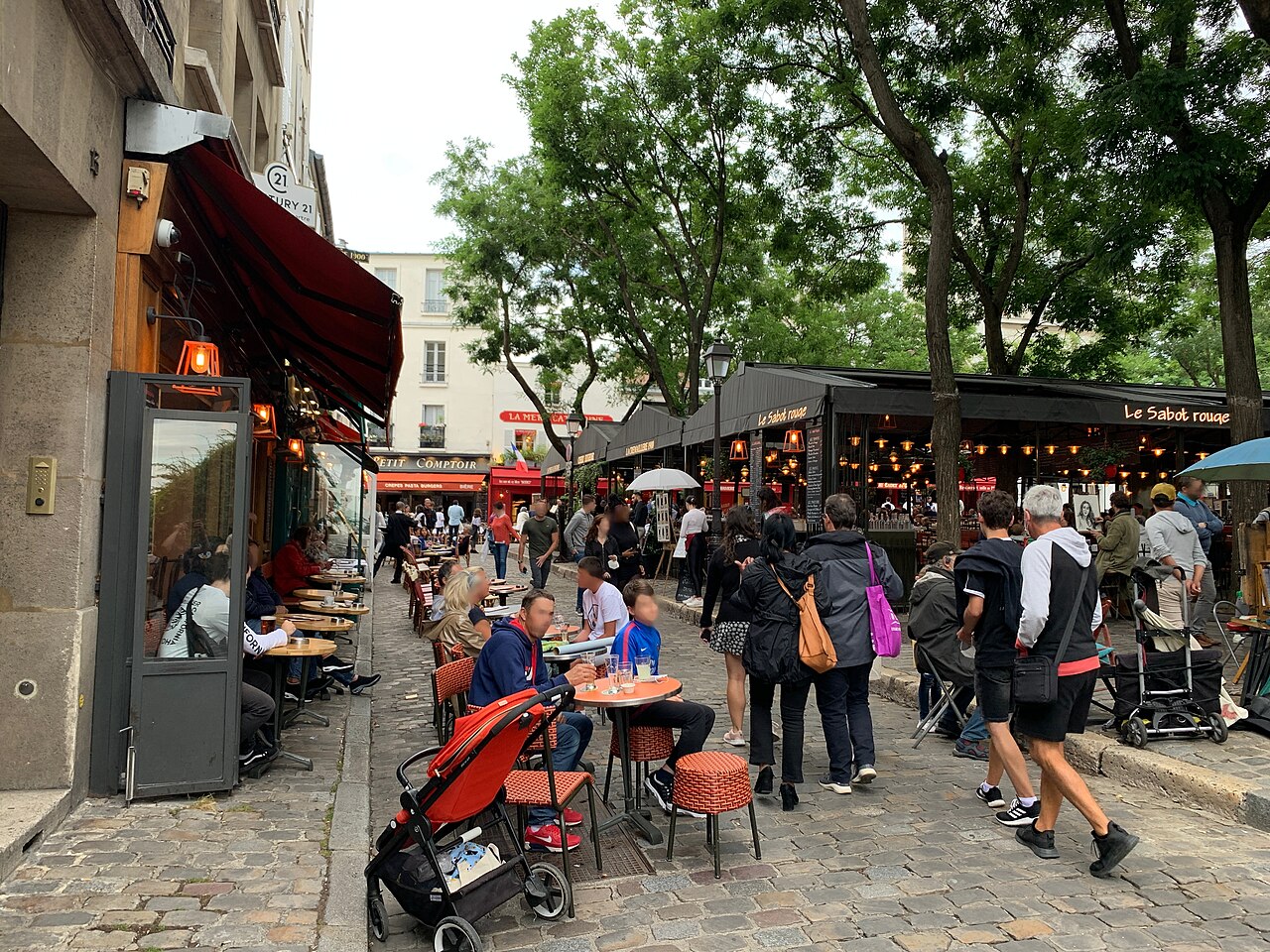 Café terraces and strollers on the Place du Tertre in Montmartre, with the Le Sabot rouge restaurant awning