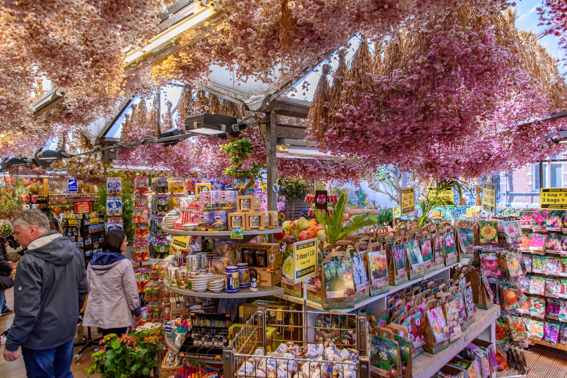 Dried flowers hanging from the ceiling above souvenirs inside a Bloemenmarkt stall