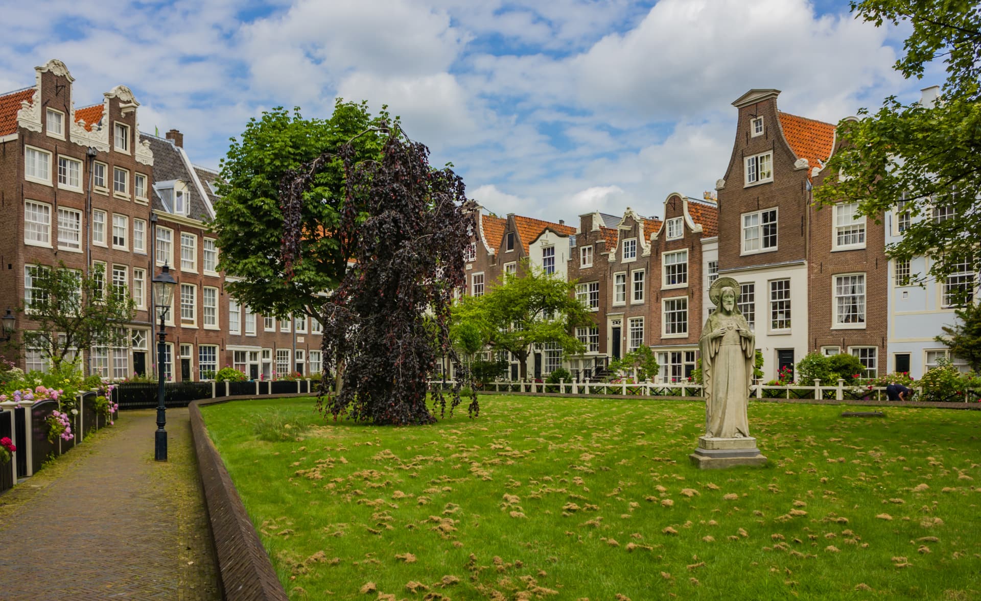 The Begijnhof courtyard in Amsterdam with its lawn, statue and gabled houses