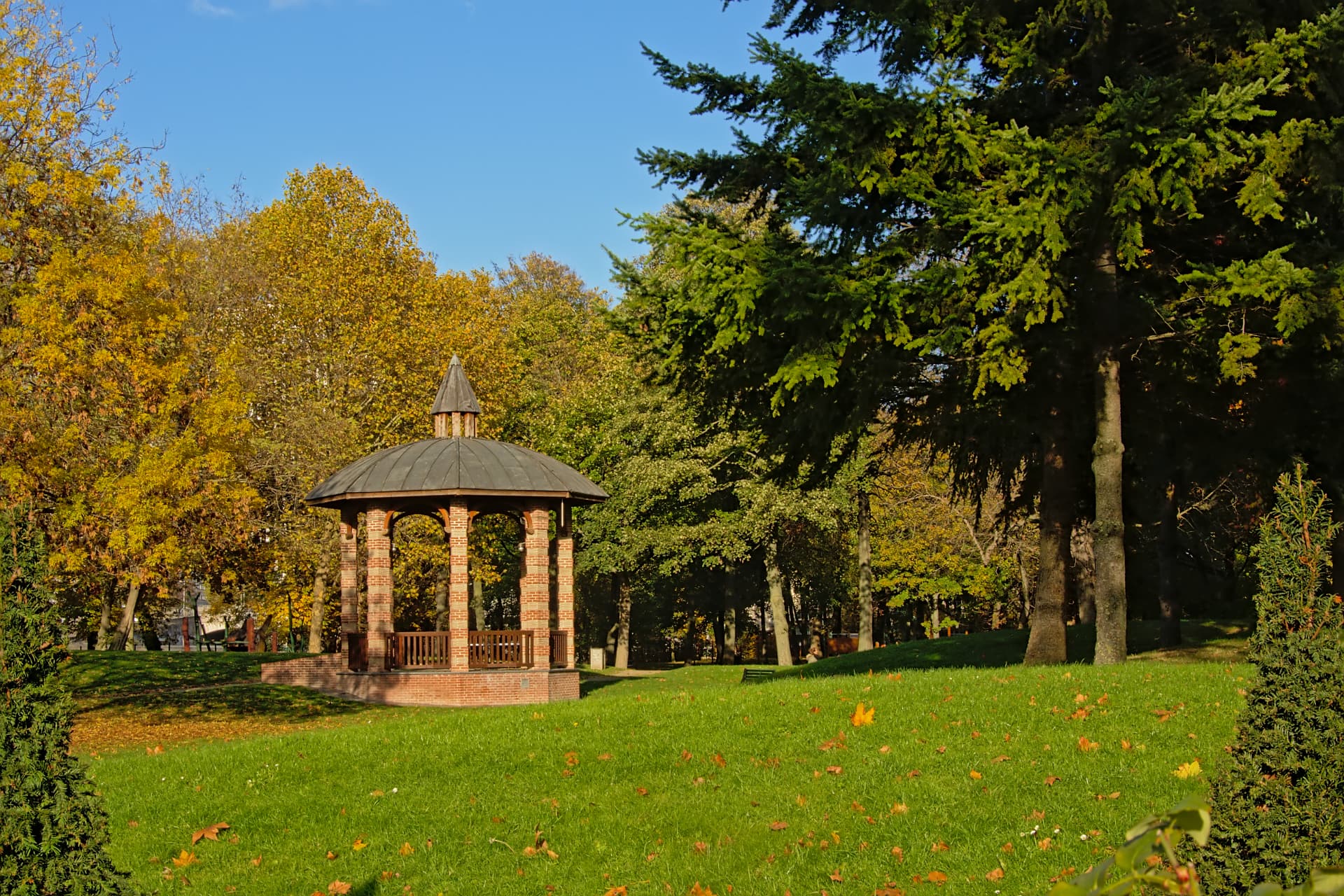 A brick gazebo on a green lawn among autumn trees in the Bois de Boulogne, Paris
