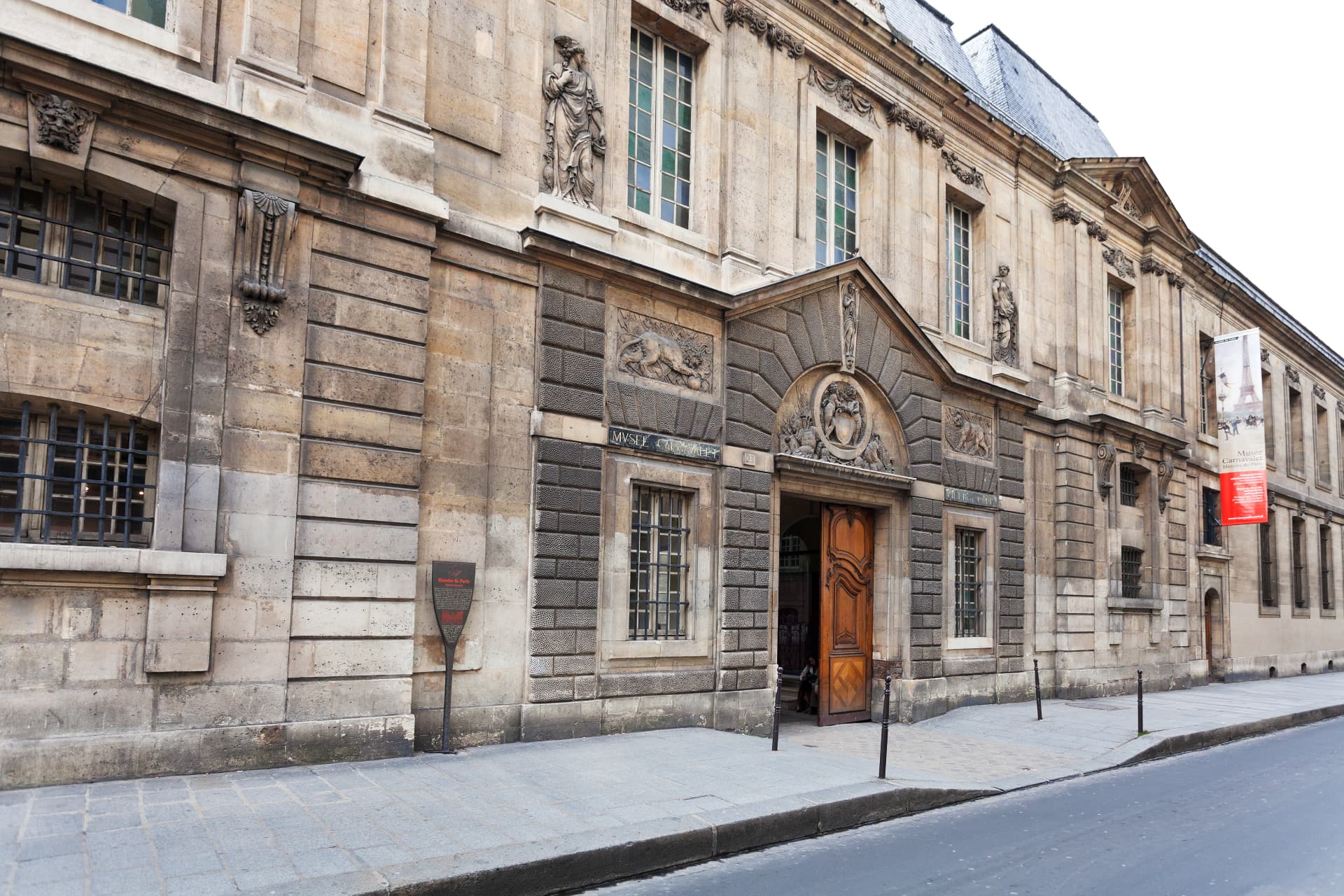 The carved stone street façade and wooden entrance door of the Musée Carnavalet on Rue de Sévigné