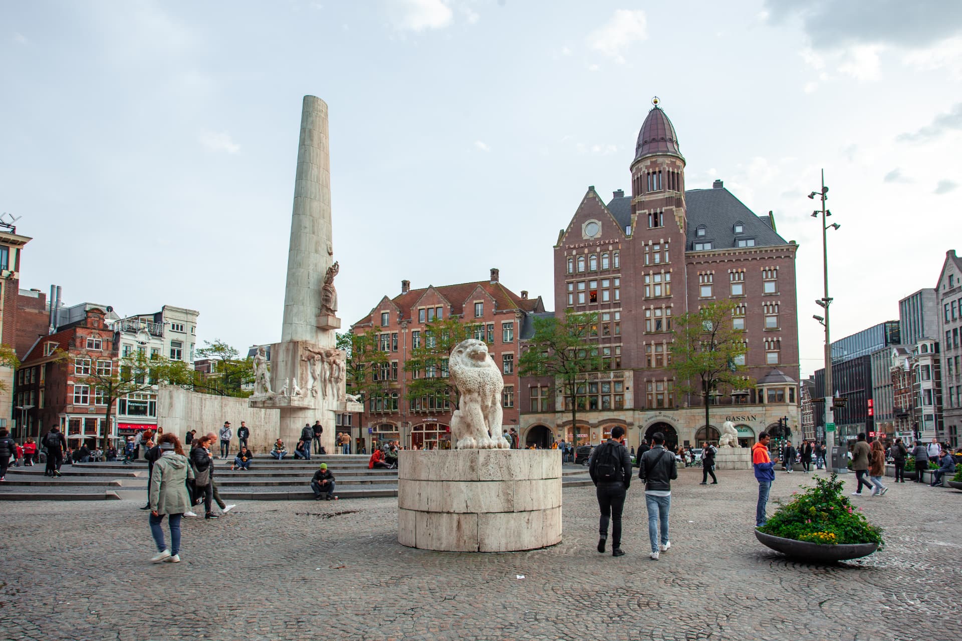Dam Square in Amsterdam with the National Monument obelisk, stone lions and historic gabled buildings