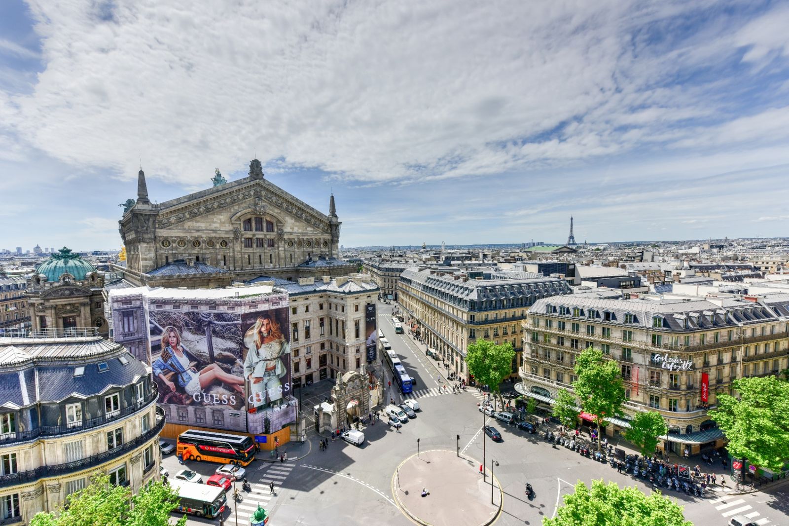 Paris skyline from Galeries Lafayette rooftop, with the Eiffel Tower and Palais Garnier visible across the Haussmann rooftops