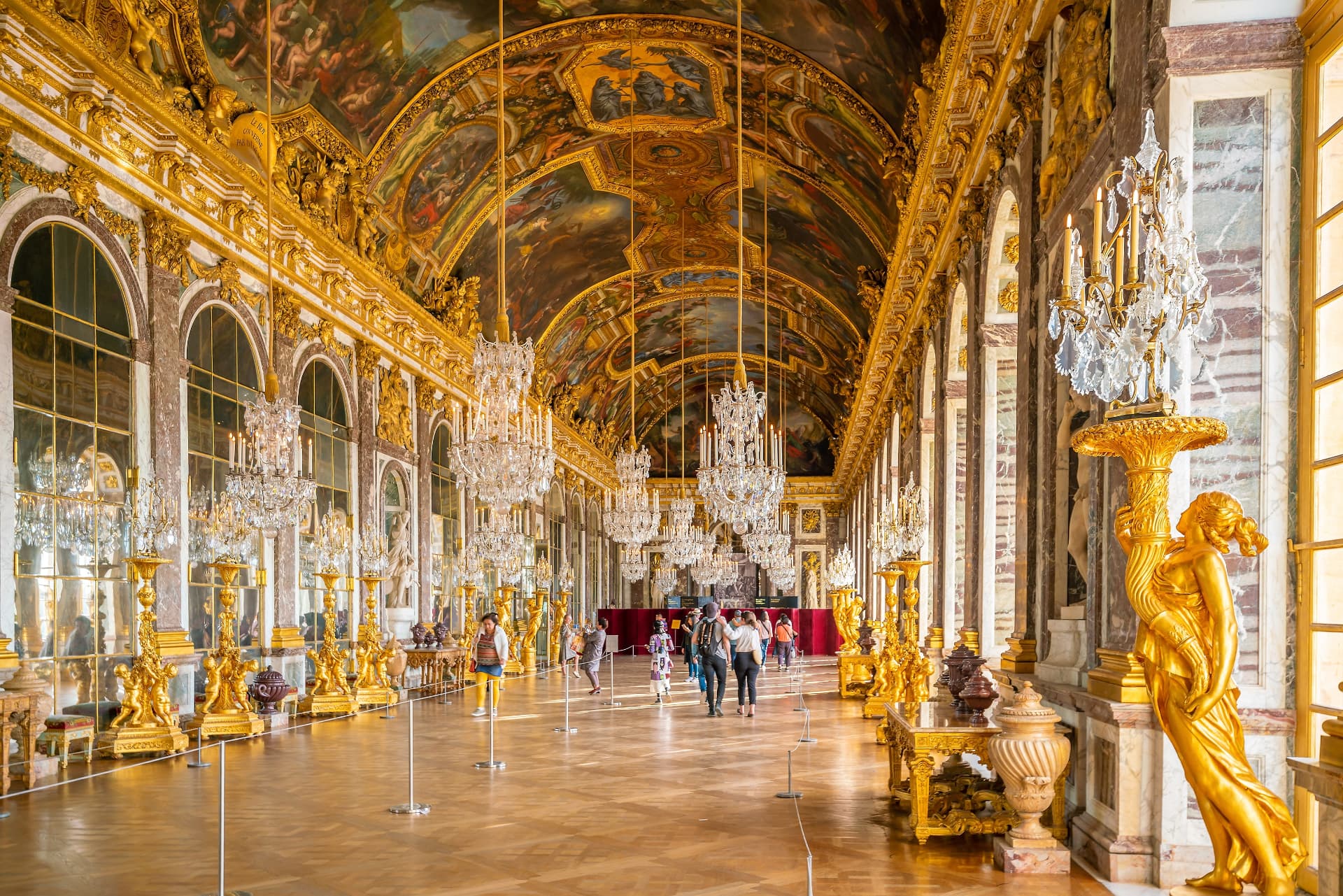The Hall of Mirrors at Versailles with gilded decoration, painted ceiling and rows of crystal chandeliers