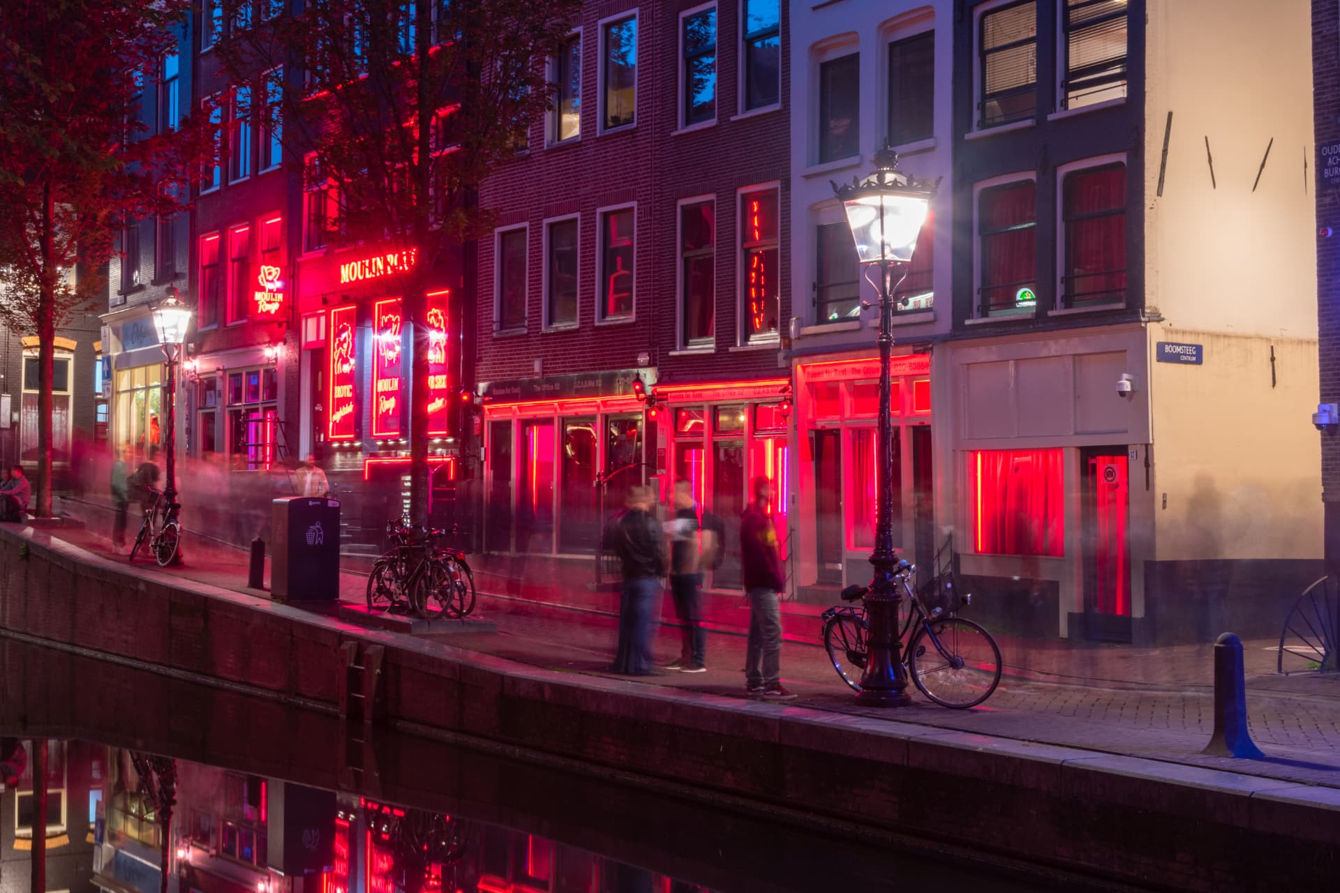 Neon-lit windows and canal houses along the Red Light District in De Wallen, Amsterdam