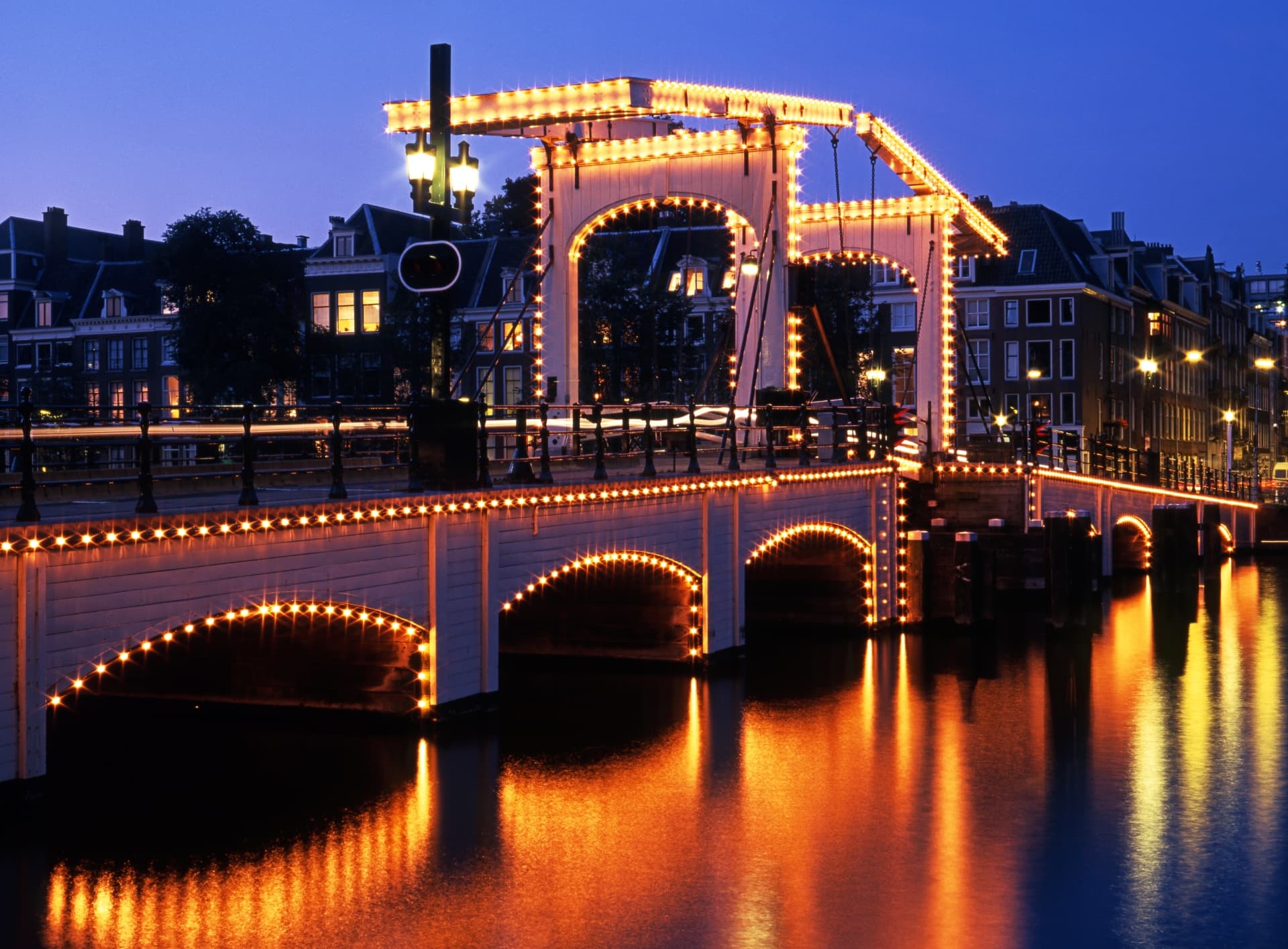 Close view of the Magere Brug's illuminated white timber frame and arches at night in Amsterdam