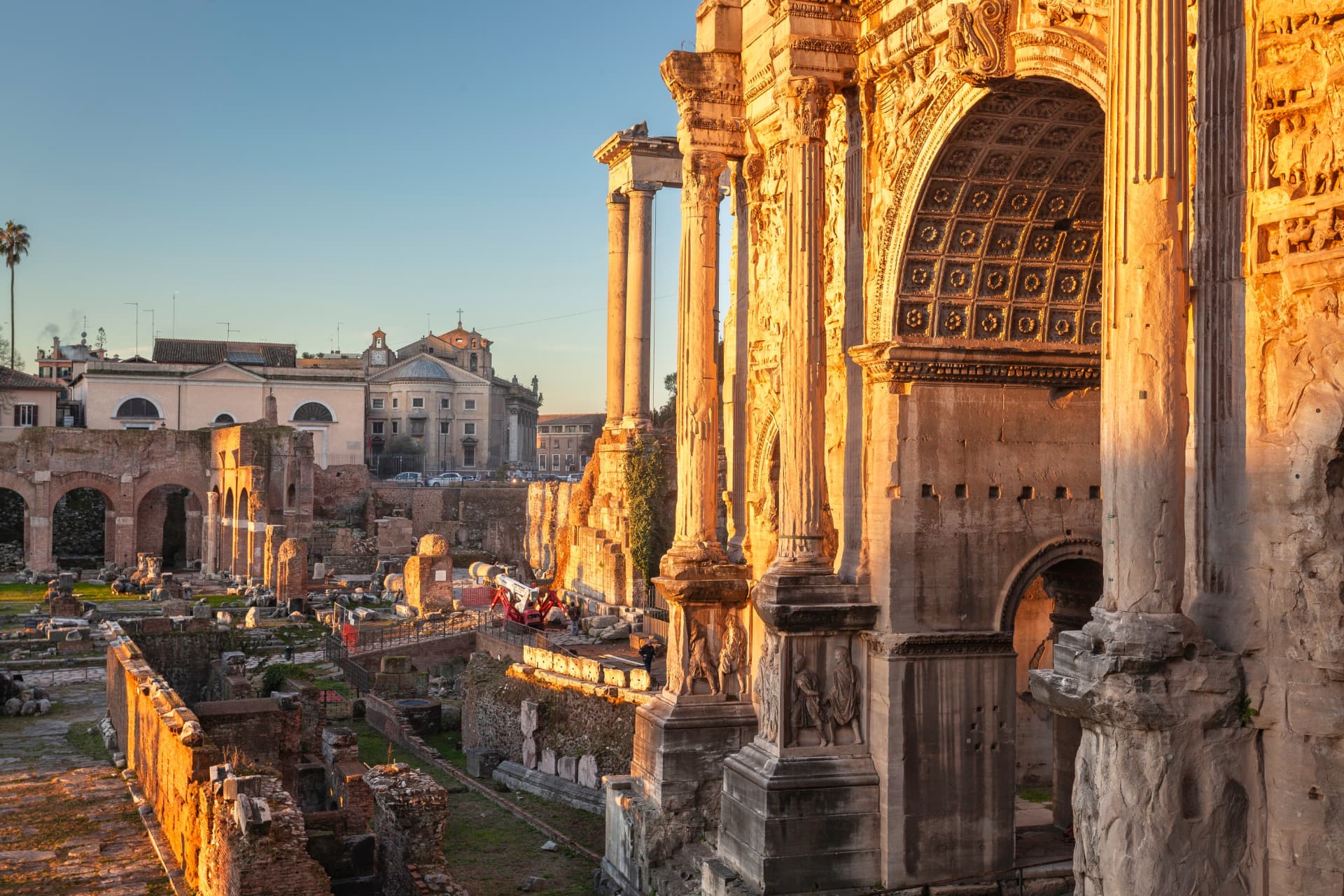 Arch of Septimius Severus in golden evening light with the Temple of Vespasian columns behind