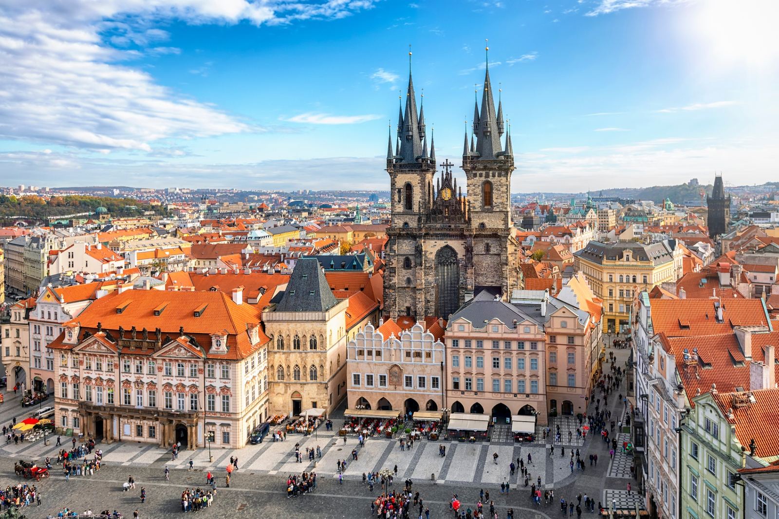 Aerial view of Prague's Old Town Square with the Church of Our Lady before Týn, red rooftops and the historic city center under a bright blue sky