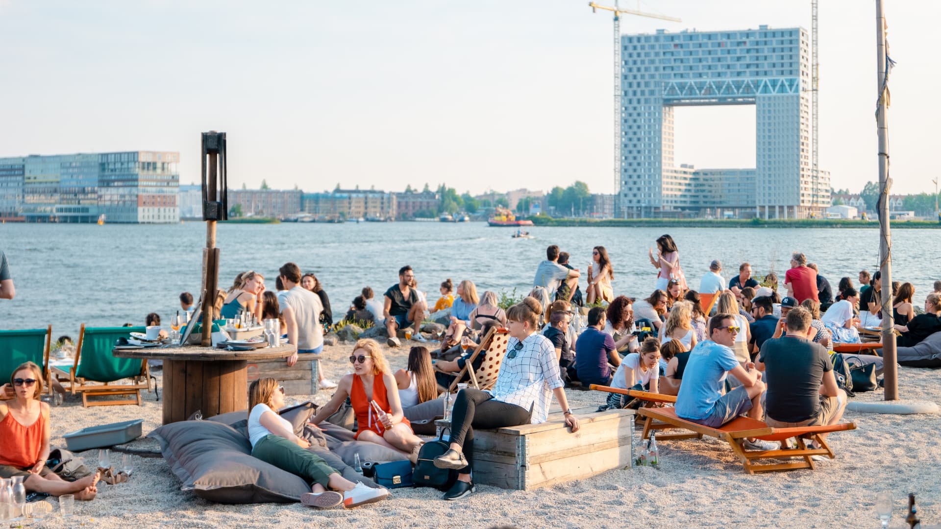 Crowds enjoying a beach bar at NDSM Wharf in Amsterdam with the Pontsteiger building in the background