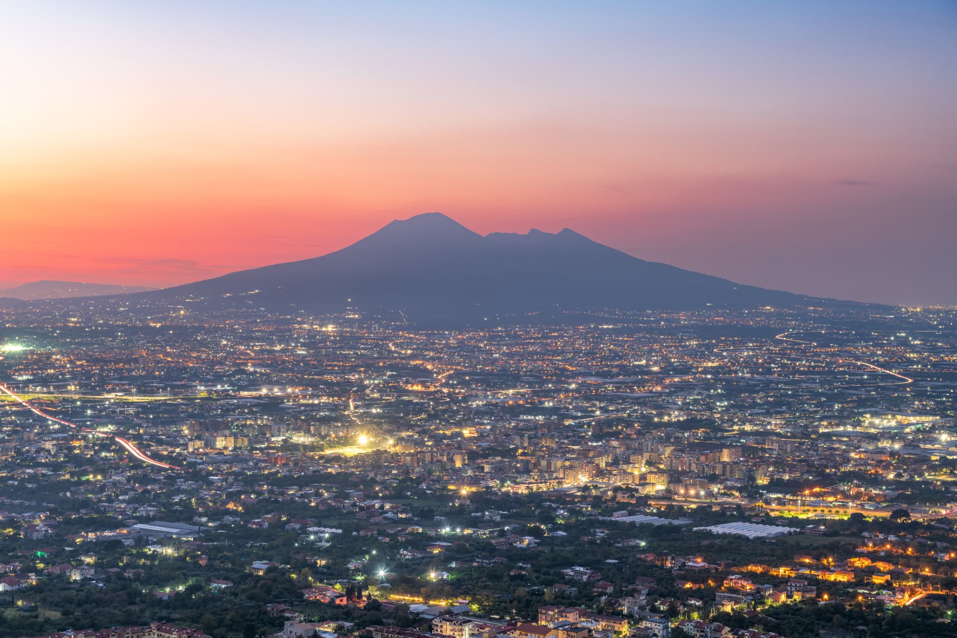 Mount Vesuvius at sunset above the lit towns of the bay of Naples