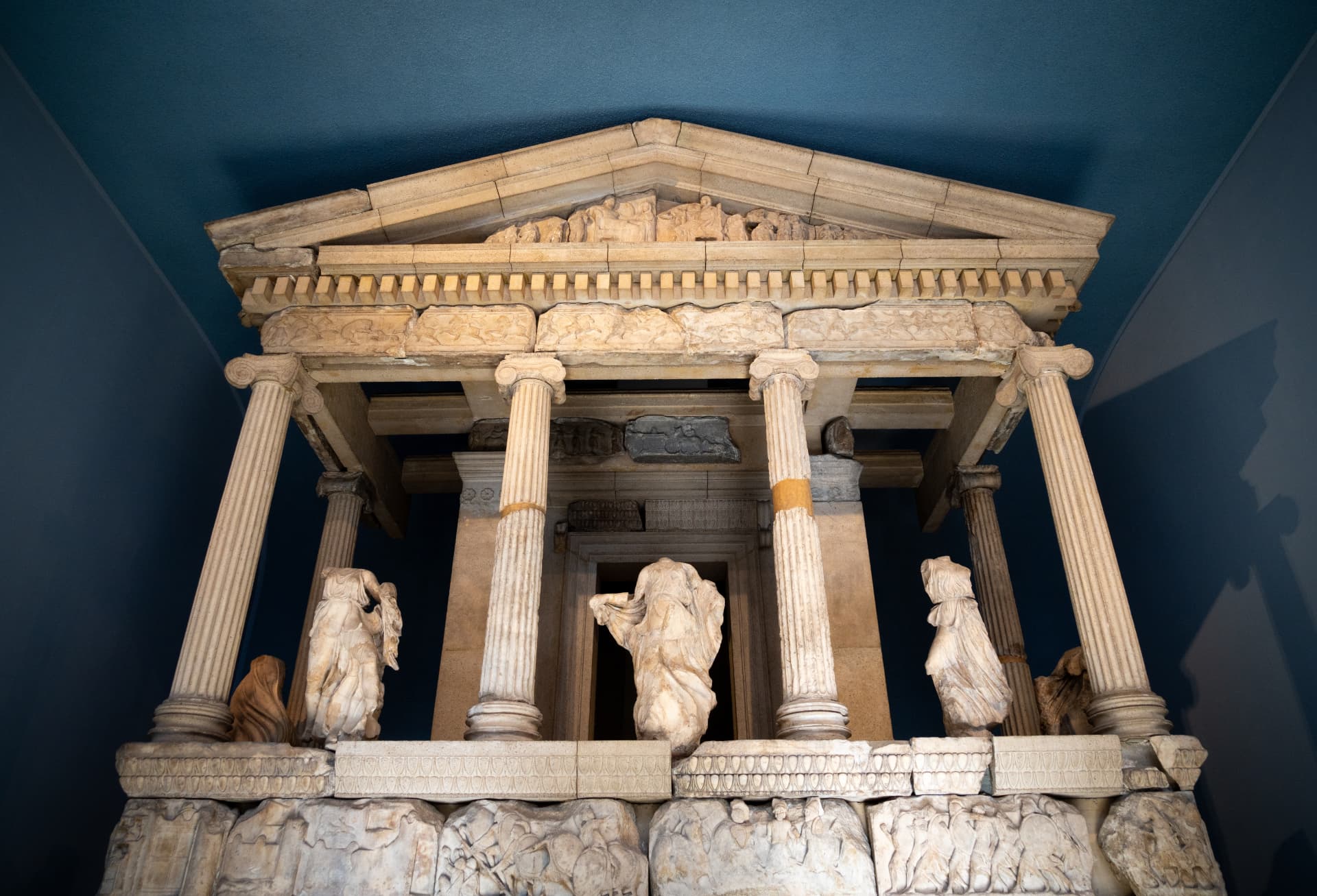 A monumental classical display inside a British Museum gallery beneath a dark blue ceiling