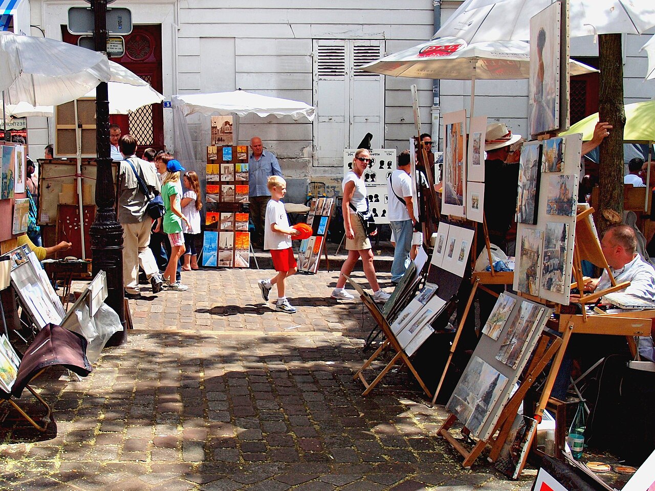 Painters' easels and artwork displays on the cobbled Place du Tertre in Montmartre, Paris