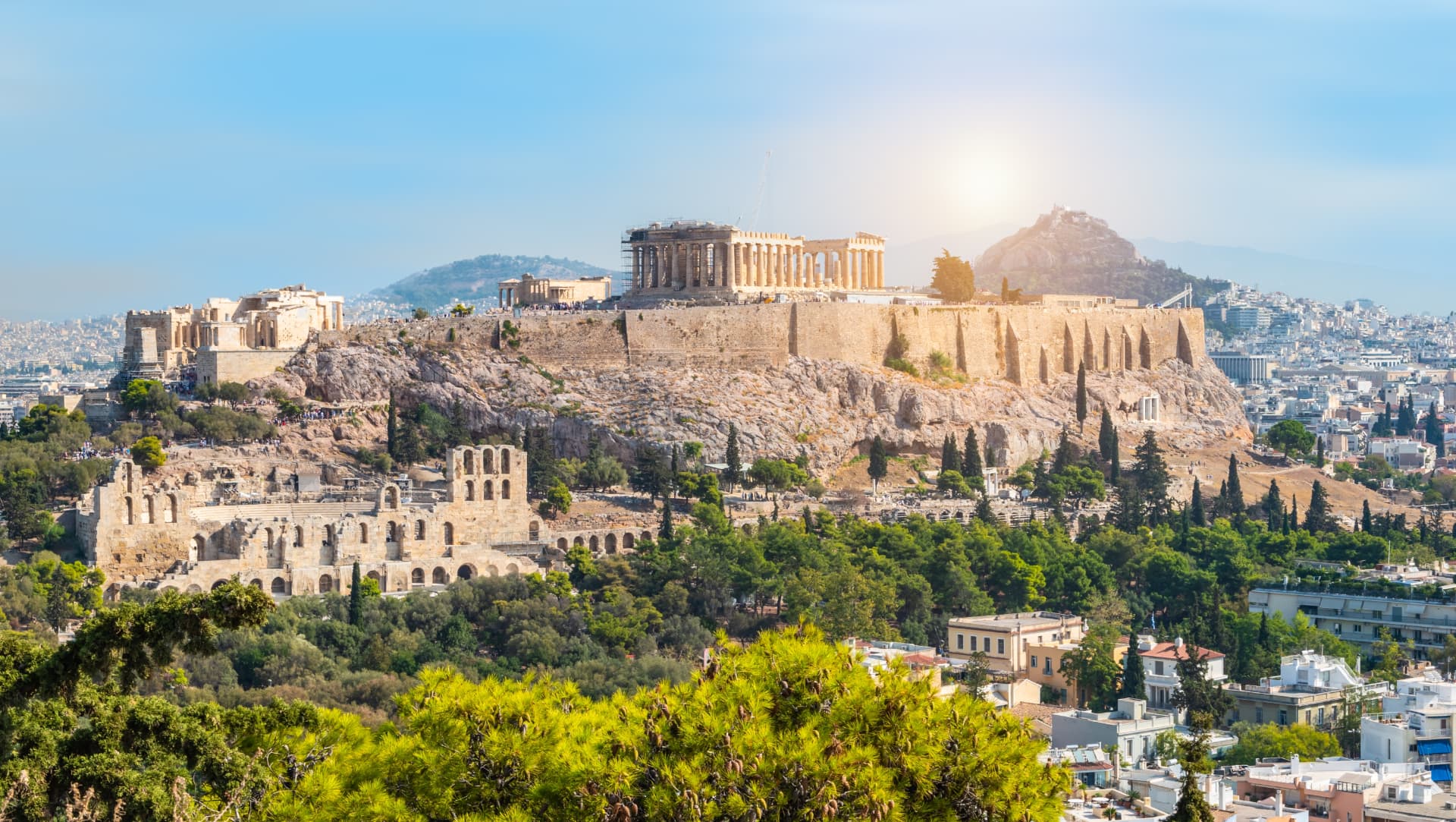 Wide view of the Acropolis hill in bright sunshine with the Odeon of Herodes Atticus below