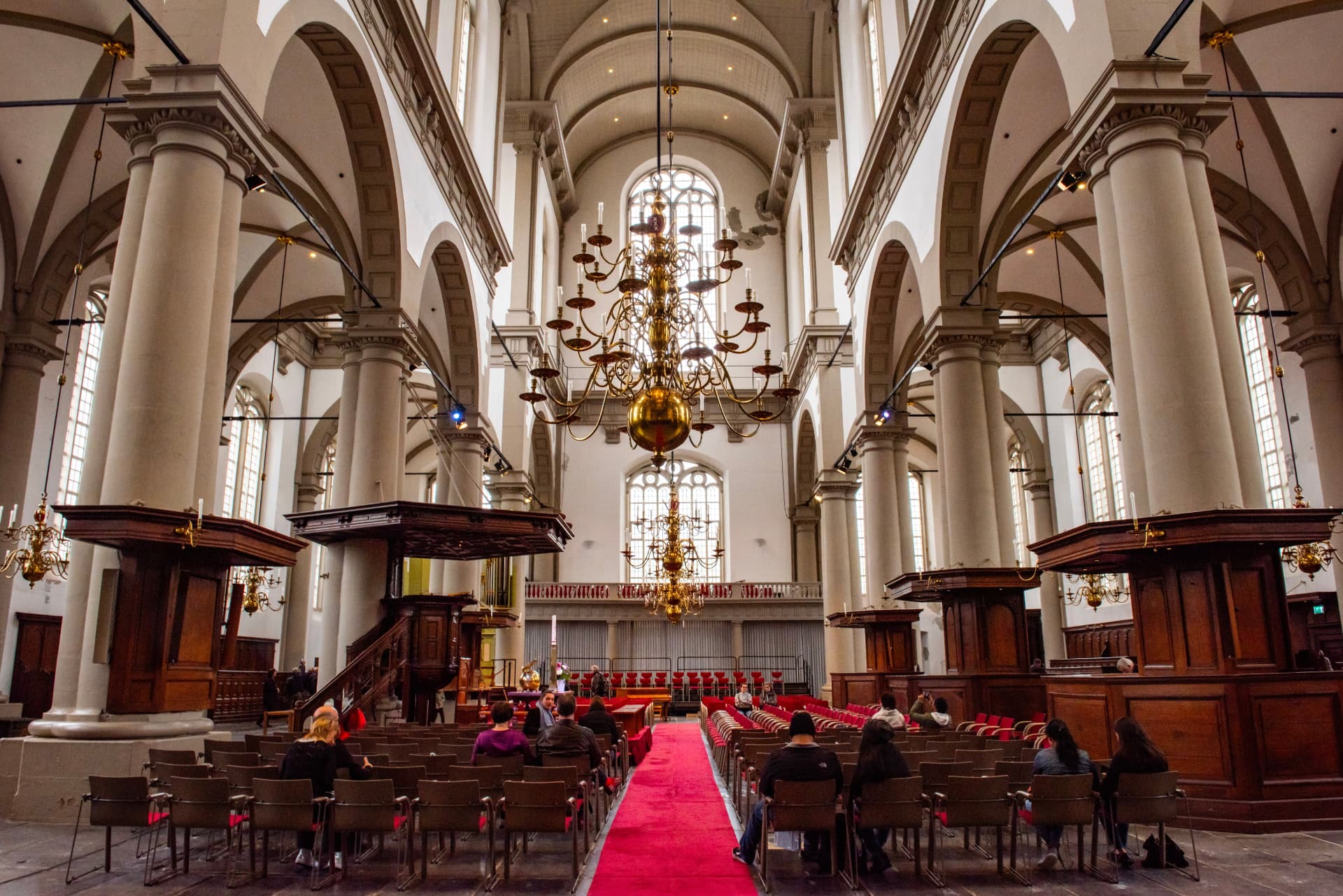 The white vaulted interior of the Westerkerk in Amsterdam with its chandeliers and wooden pulpit