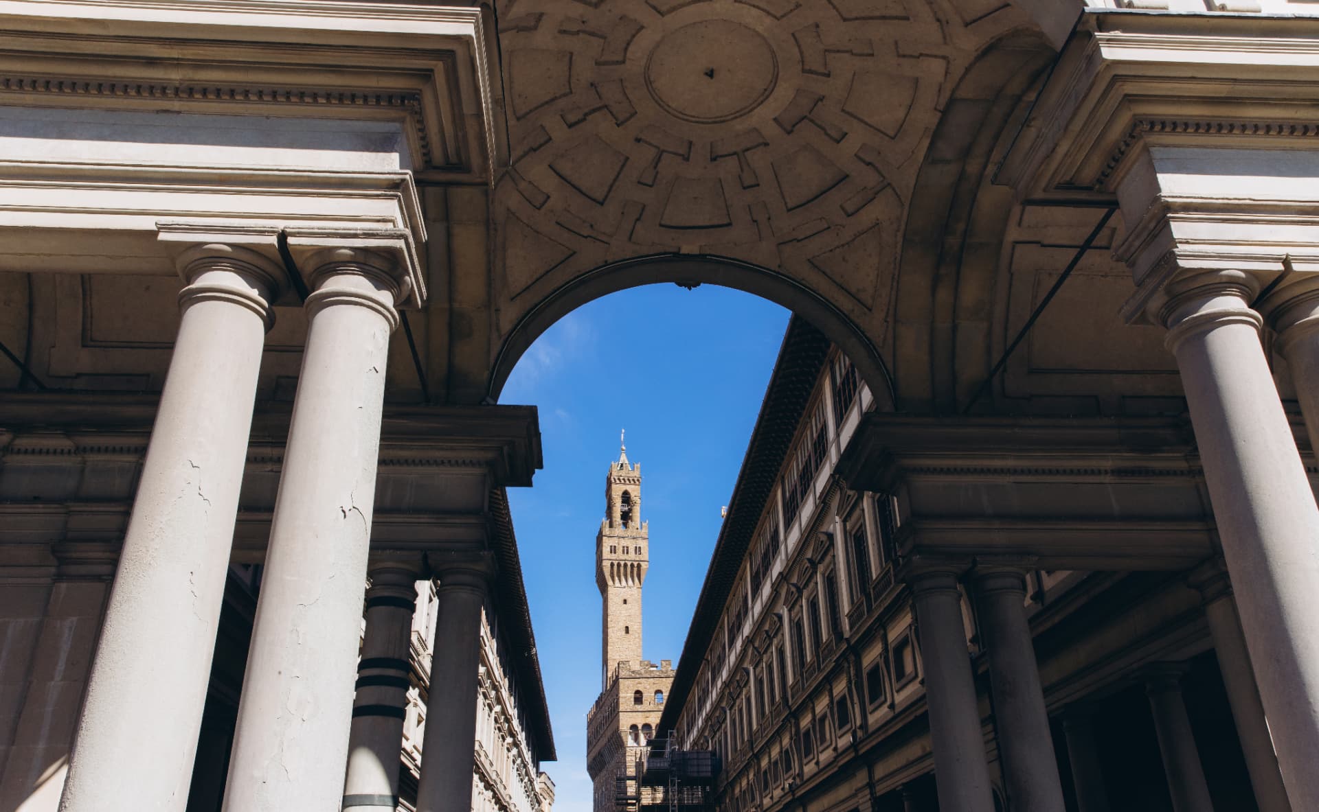Palazzo Vecchio tower framed by the Uffizi courtyard arch and stone columns