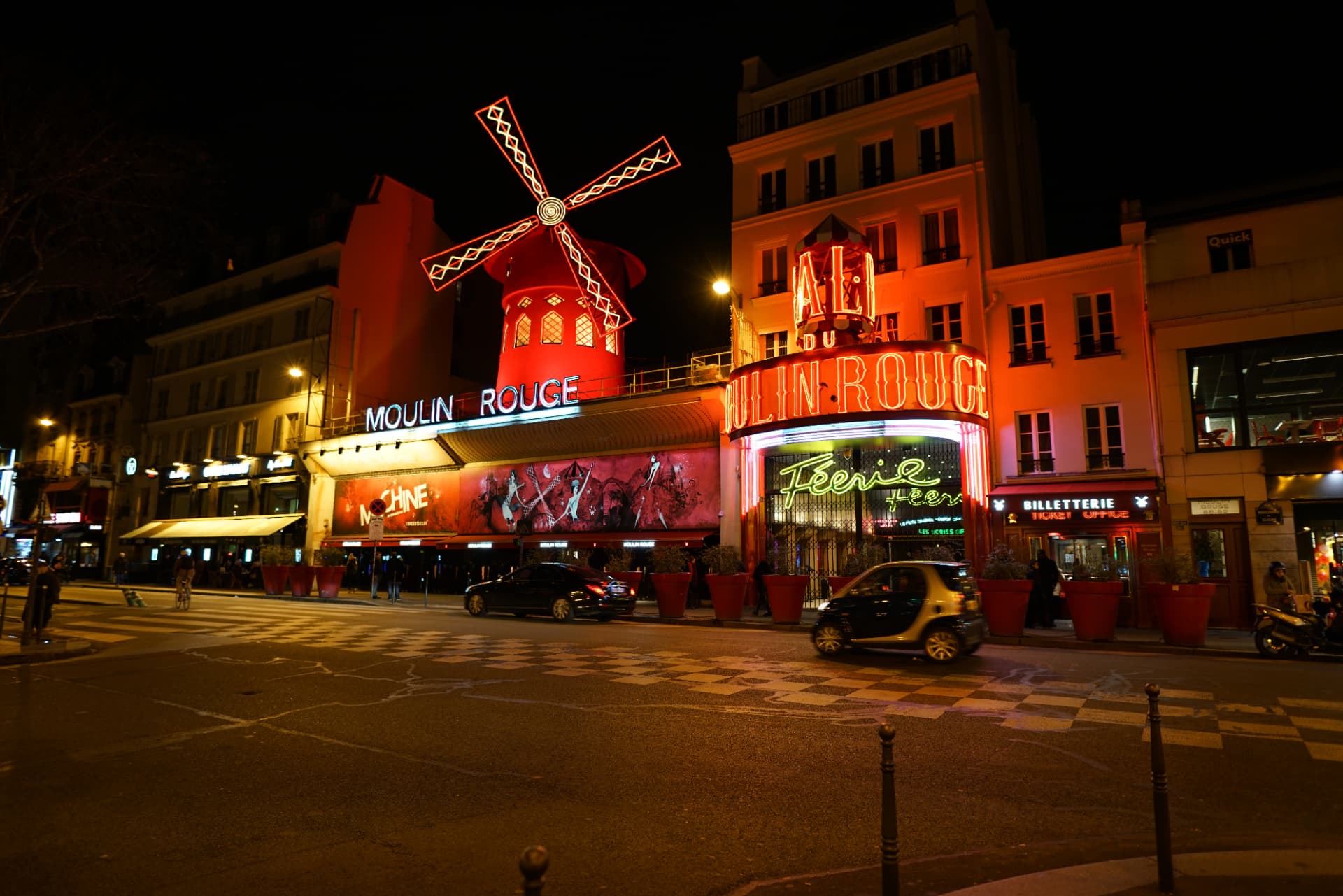 The Moulin Rouge at night, its red windmill and neon signs lit up above boulevard de Clichy in Pigalle, Paris