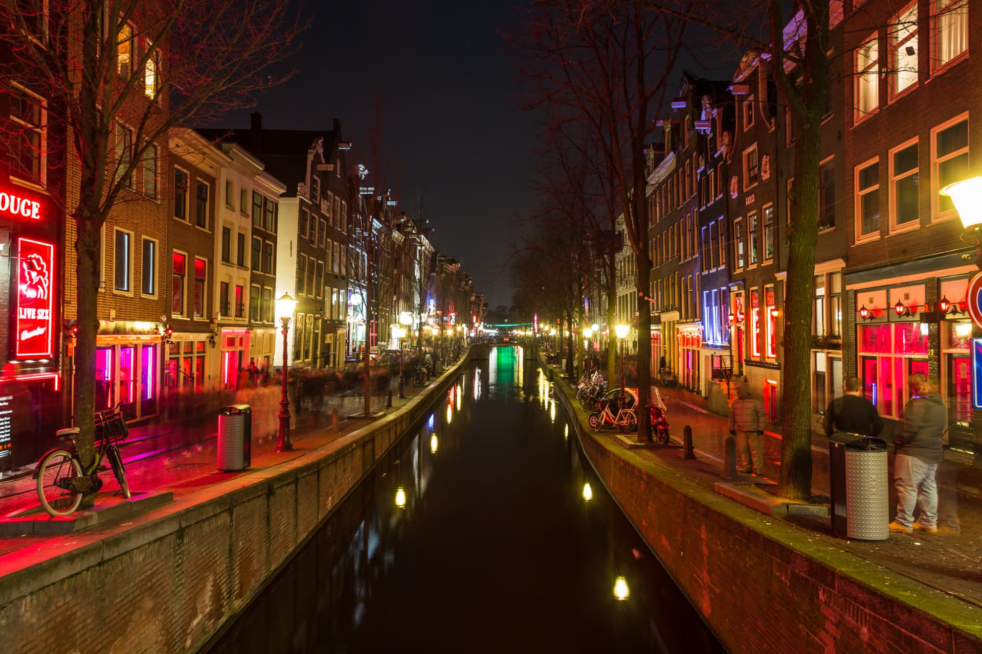 De Wallen canal at night with red neon lights reflecting on the water in Amsterdam