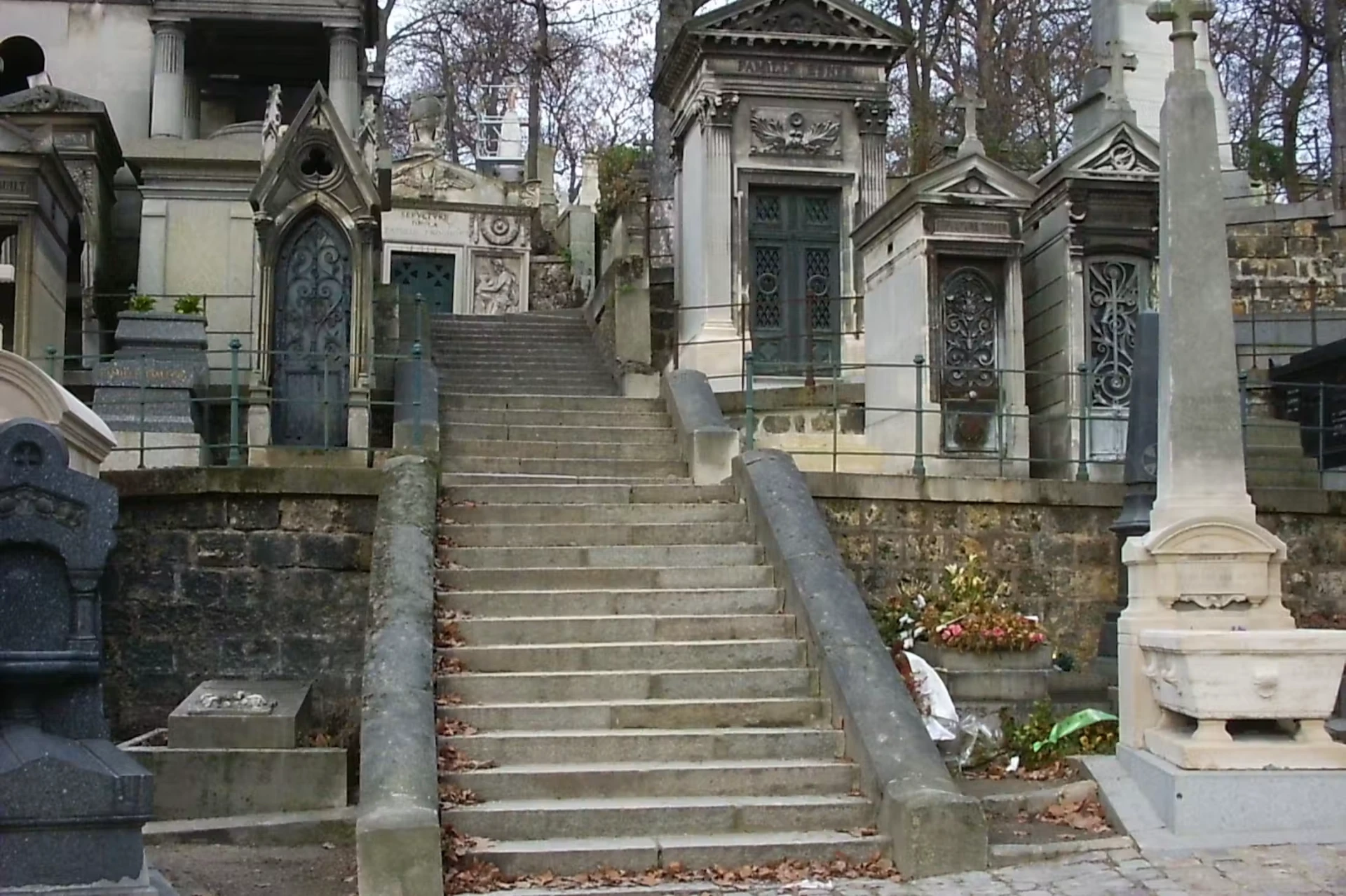 Stone steps climbing between ornate family chapels and tombs in Père Lachaise Cemetery, Paris