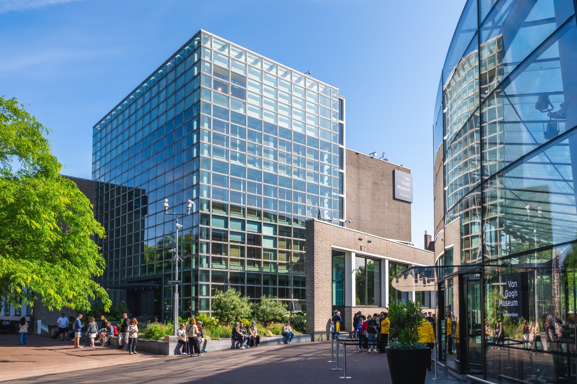 The glass entrance building of the Van Gogh Museum with trees in front