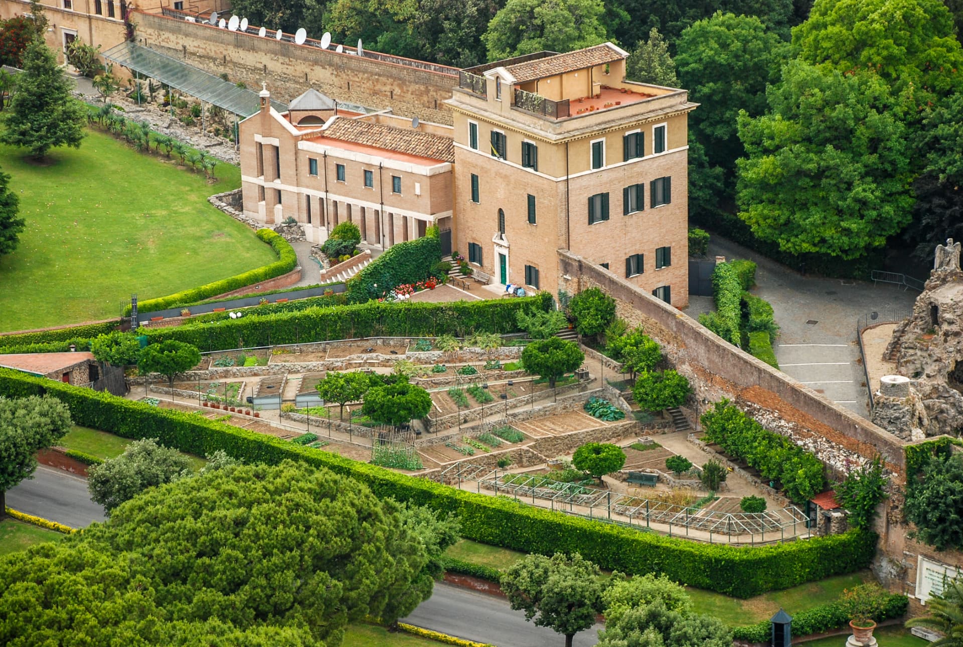 Walled garden beds and Vatican buildings amid trees
