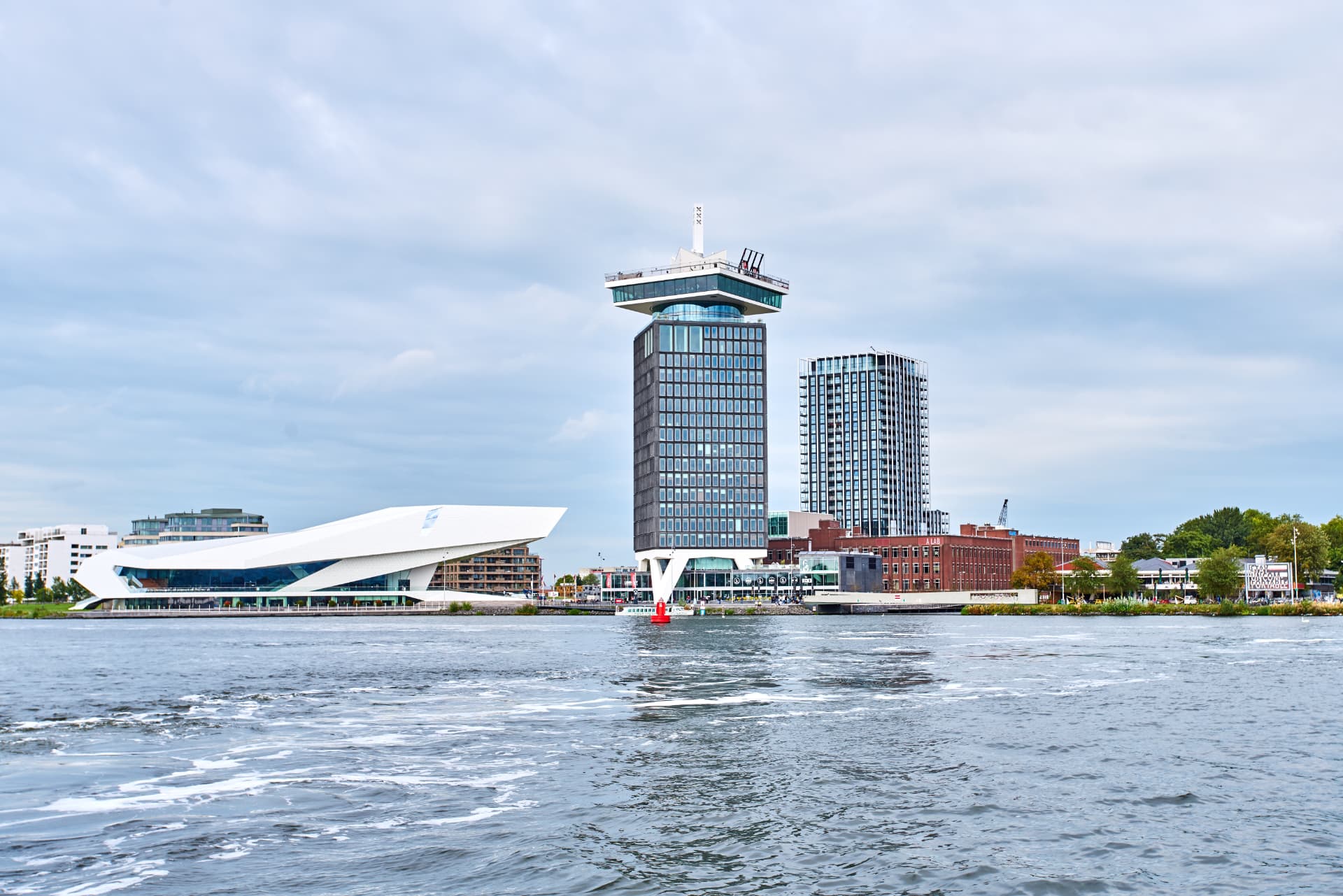 The Eye Filmmuseum and A'DAM Tower seen from a boat on the IJ river under a cloudy sky