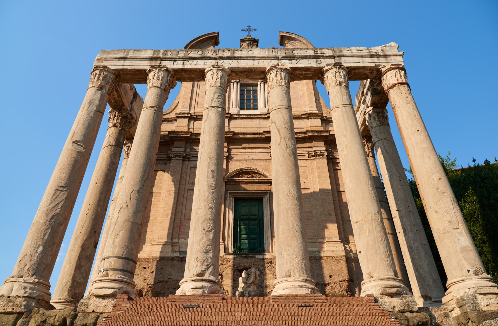 Front of the Temple of Antoninus and Faustina with inscription and church facade behind the columns