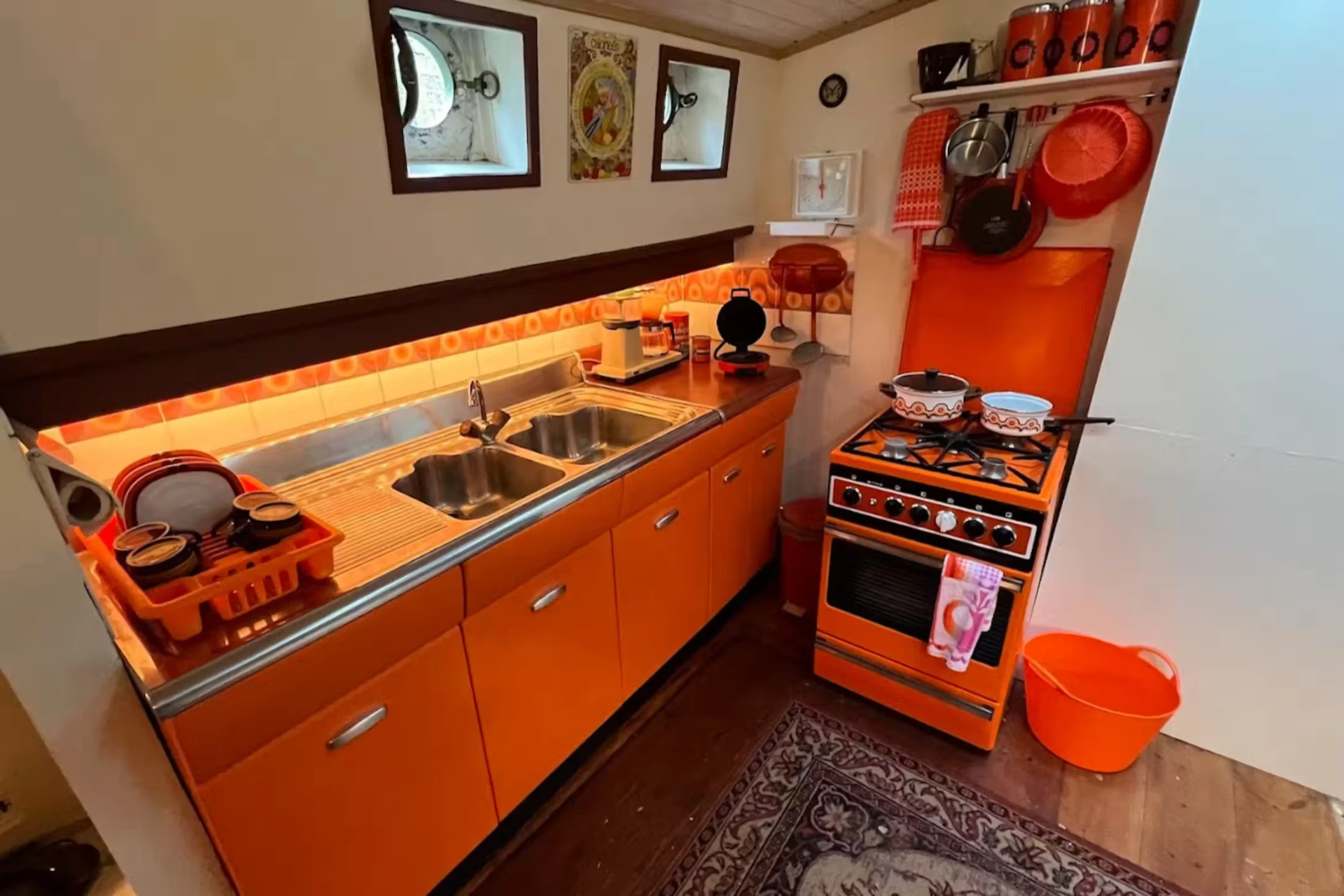 The preserved mid-century galley kitchen inside the Houseboat Museum barge in Amsterdam with orange cabinets and a gas stove