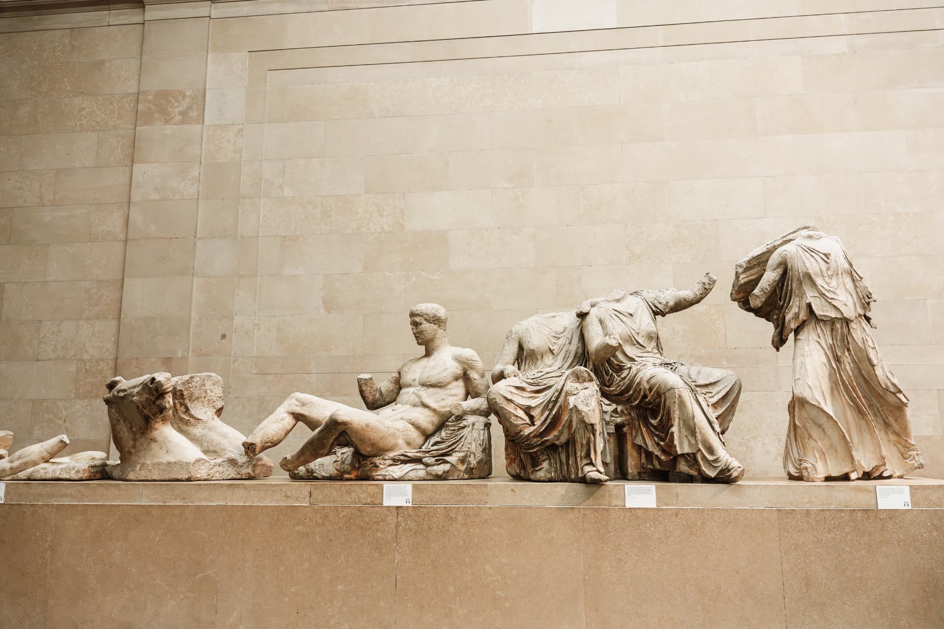 Parthenon sculptures displayed along a pale stone gallery wall inside the British Museum