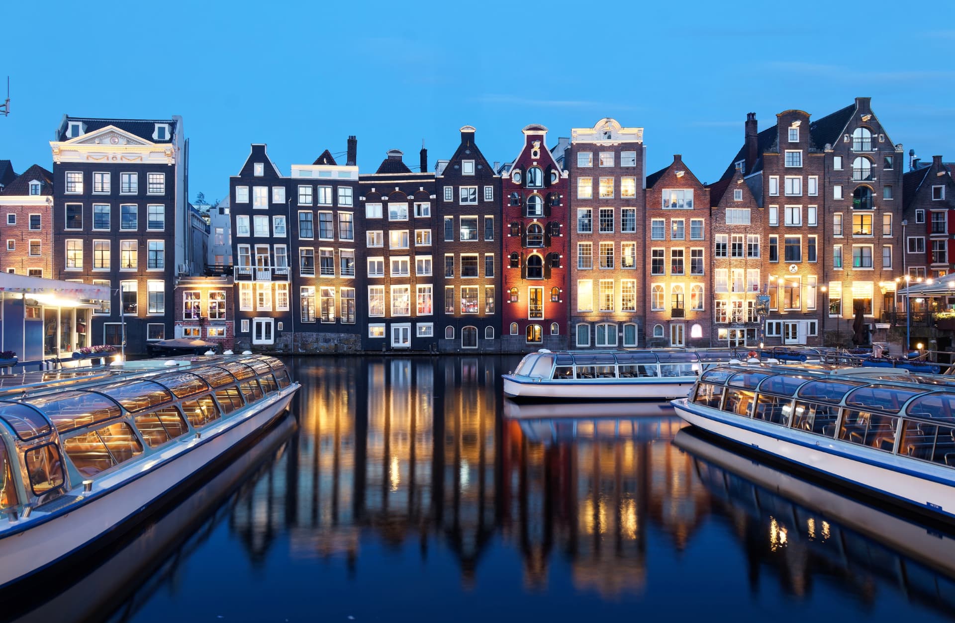 Illuminated canal houses reflected in an Amsterdam canal at dusk