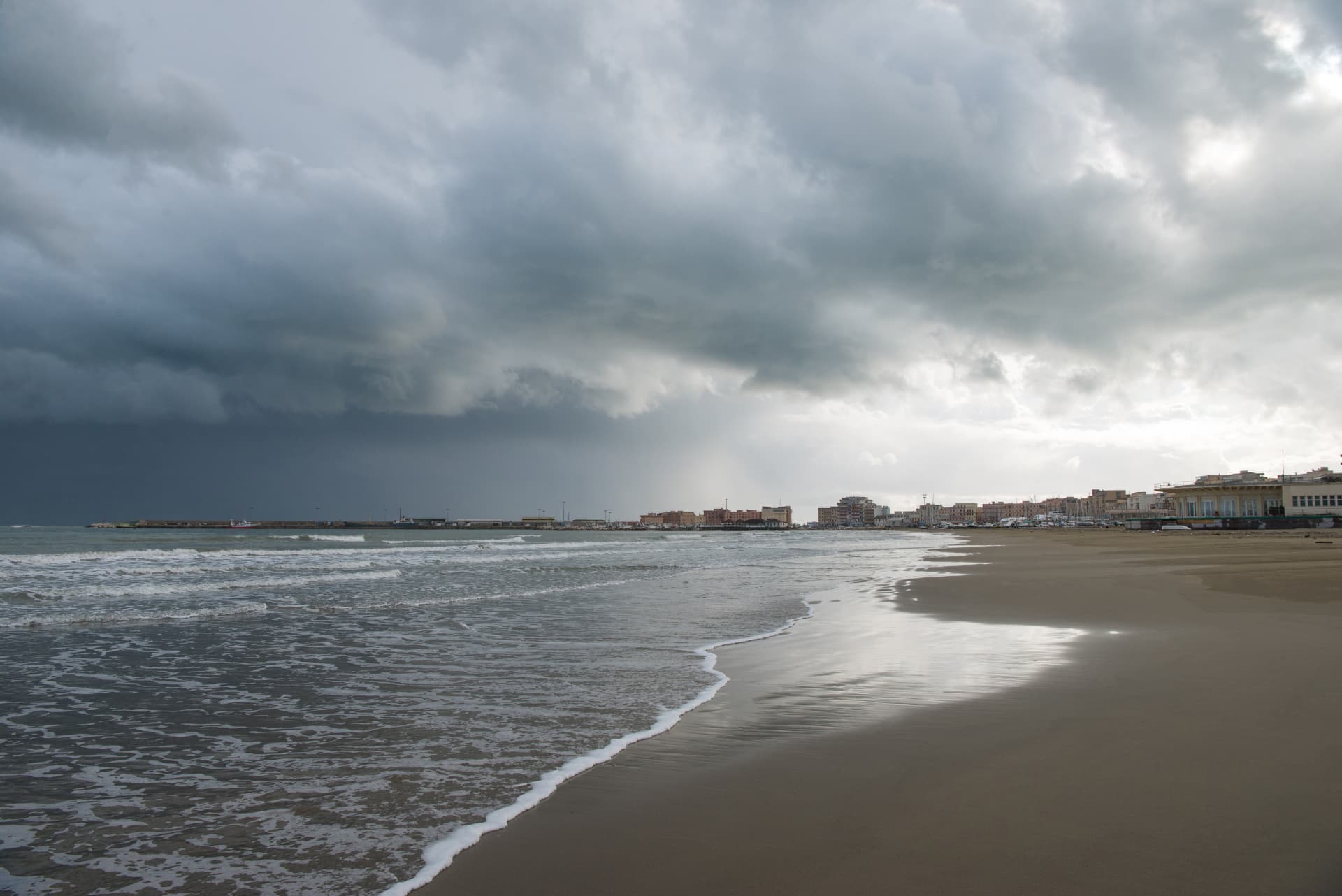 Wide sandy beach and waterfront at Anzio beneath dramatic clouds