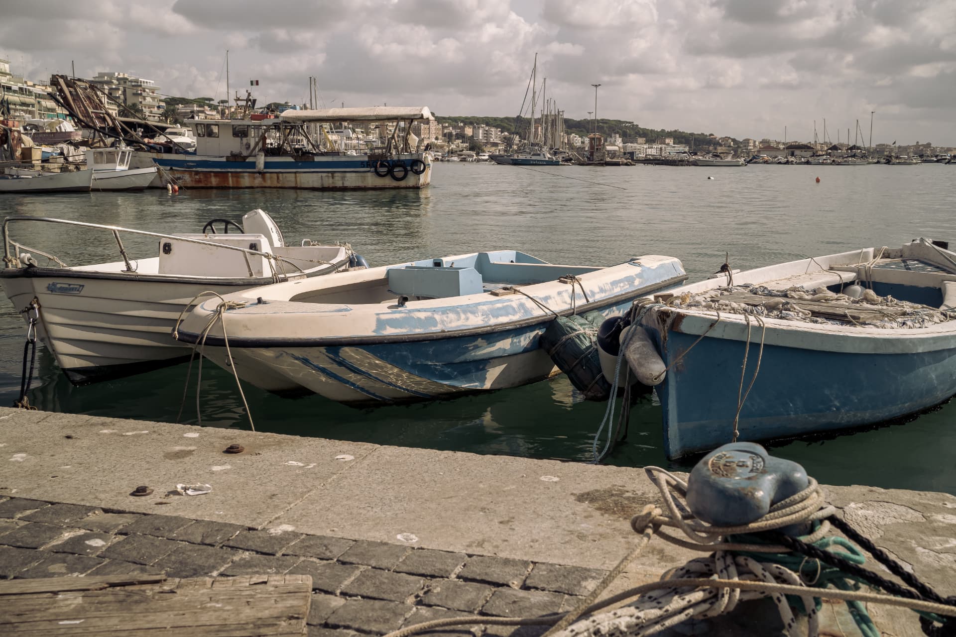 Small fishing boats tied along the quay in Anzio harbour