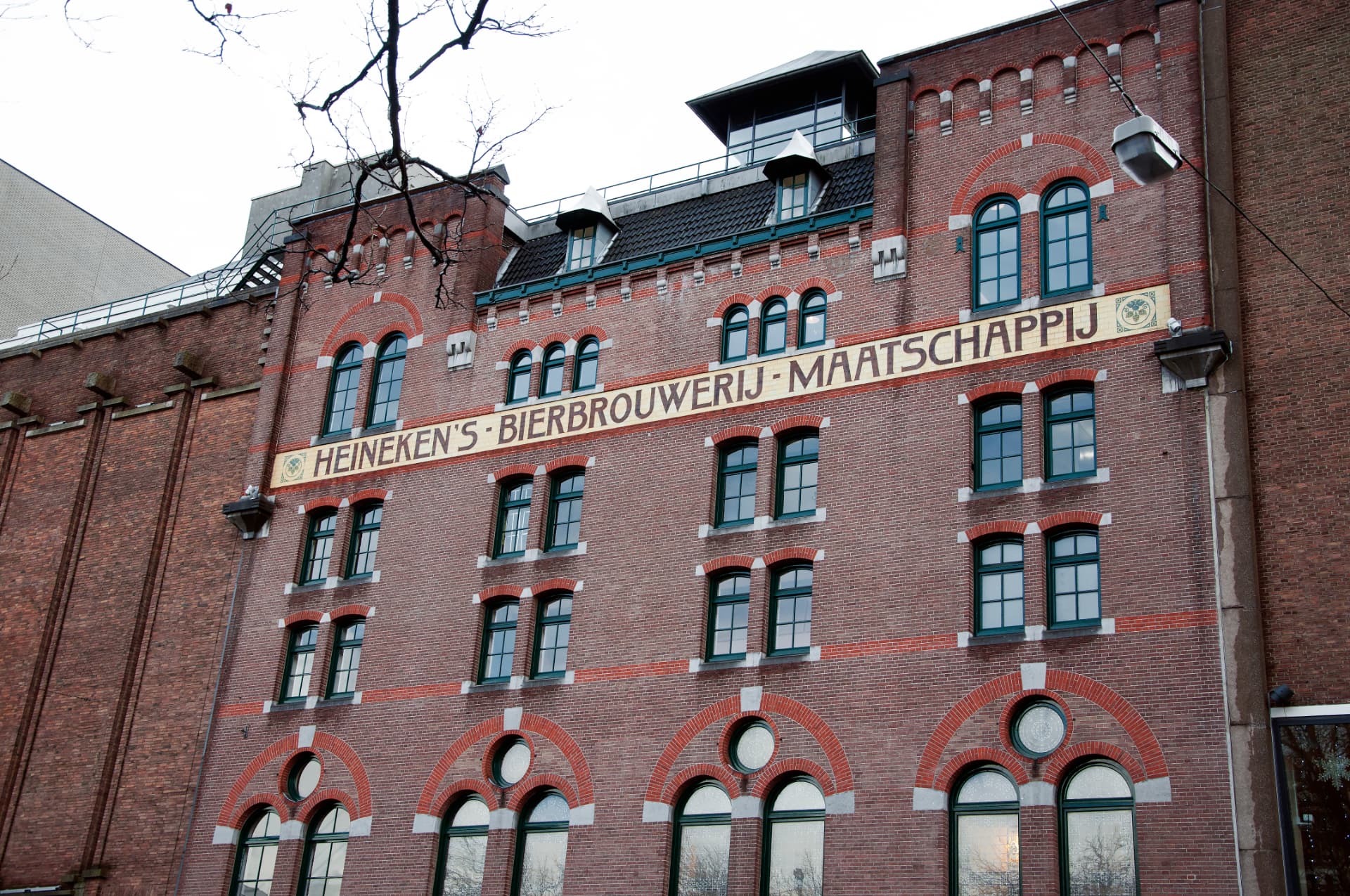 The red-brick facade of the original Heineken brewery in Amsterdam with the historic Heineken's Bierbrouwerij-Maatschappij lettering