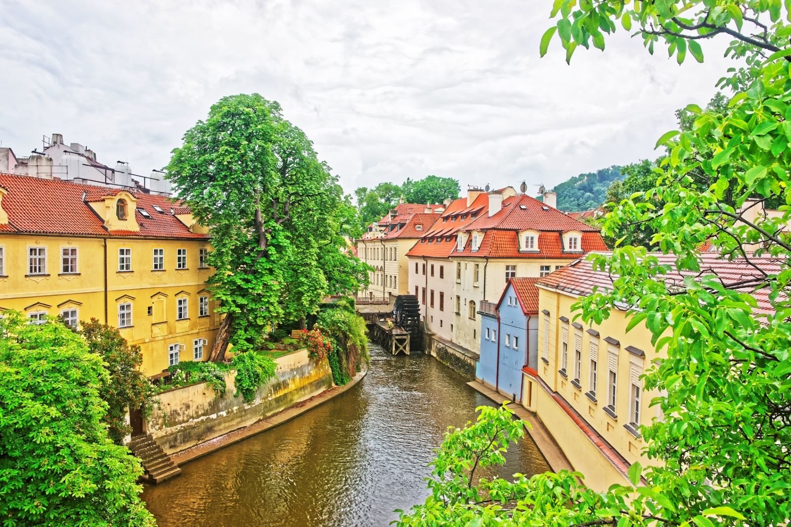 Čertovka channel winding through Kampa Island in Prague with colorful riverside houses and a historic water wheel