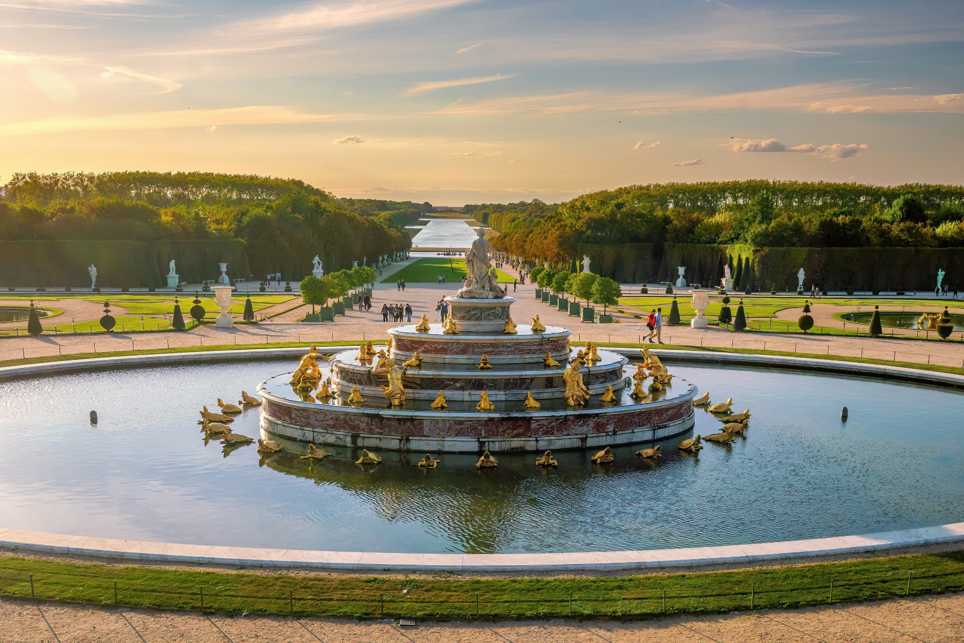 Latona Fountain at sunset with the long green axis and Grand Canal stretching through the Versailles Gardens