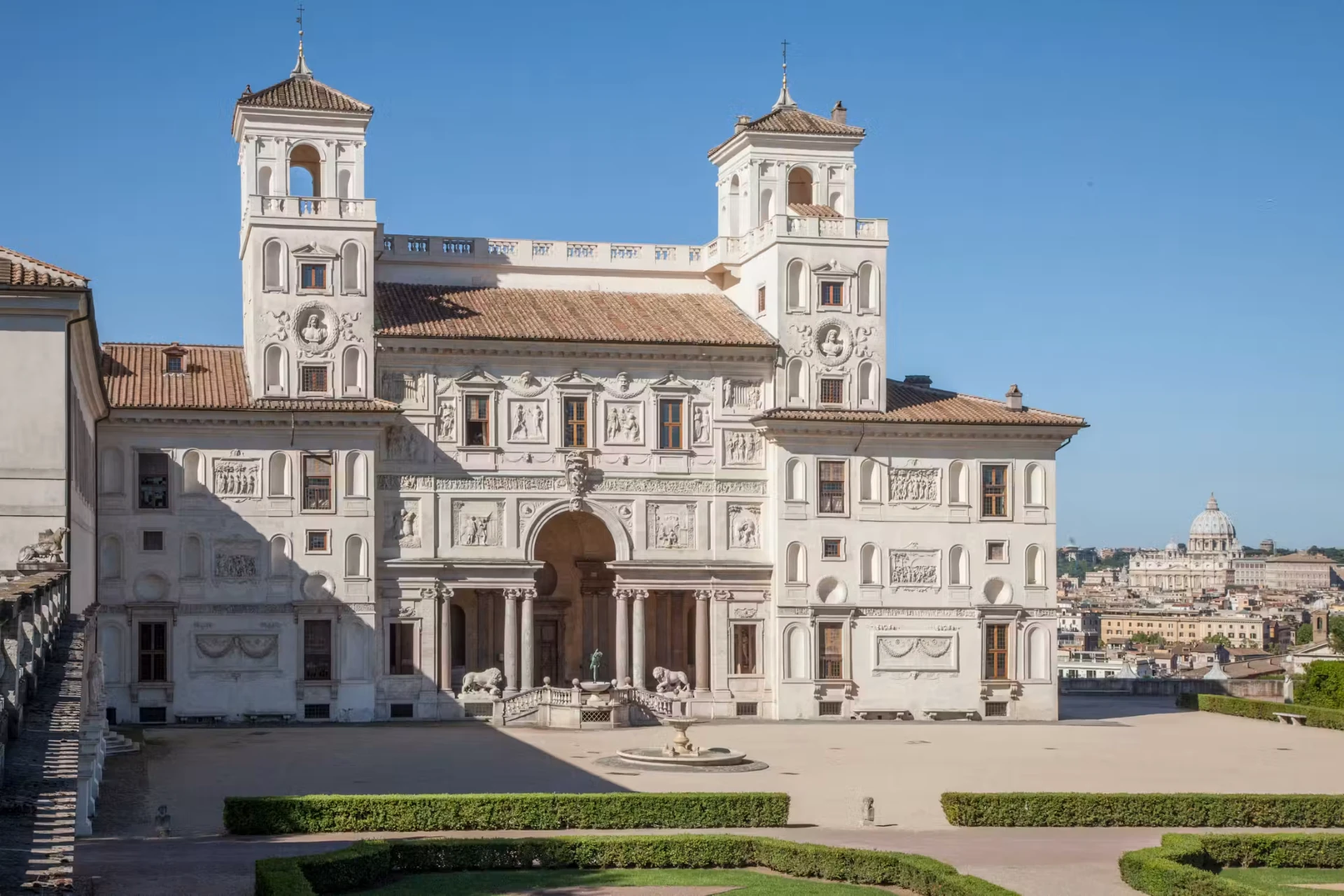 Relief-covered garden façade of Villa Medici with twin towers, lions and St Peter’s dome in the distance