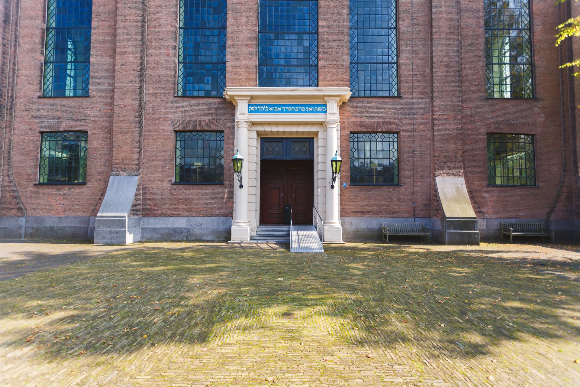 The entrance of the Portuguese Synagogue in Amsterdam with a Hebrew inscription above the door and a quiet brick courtyard