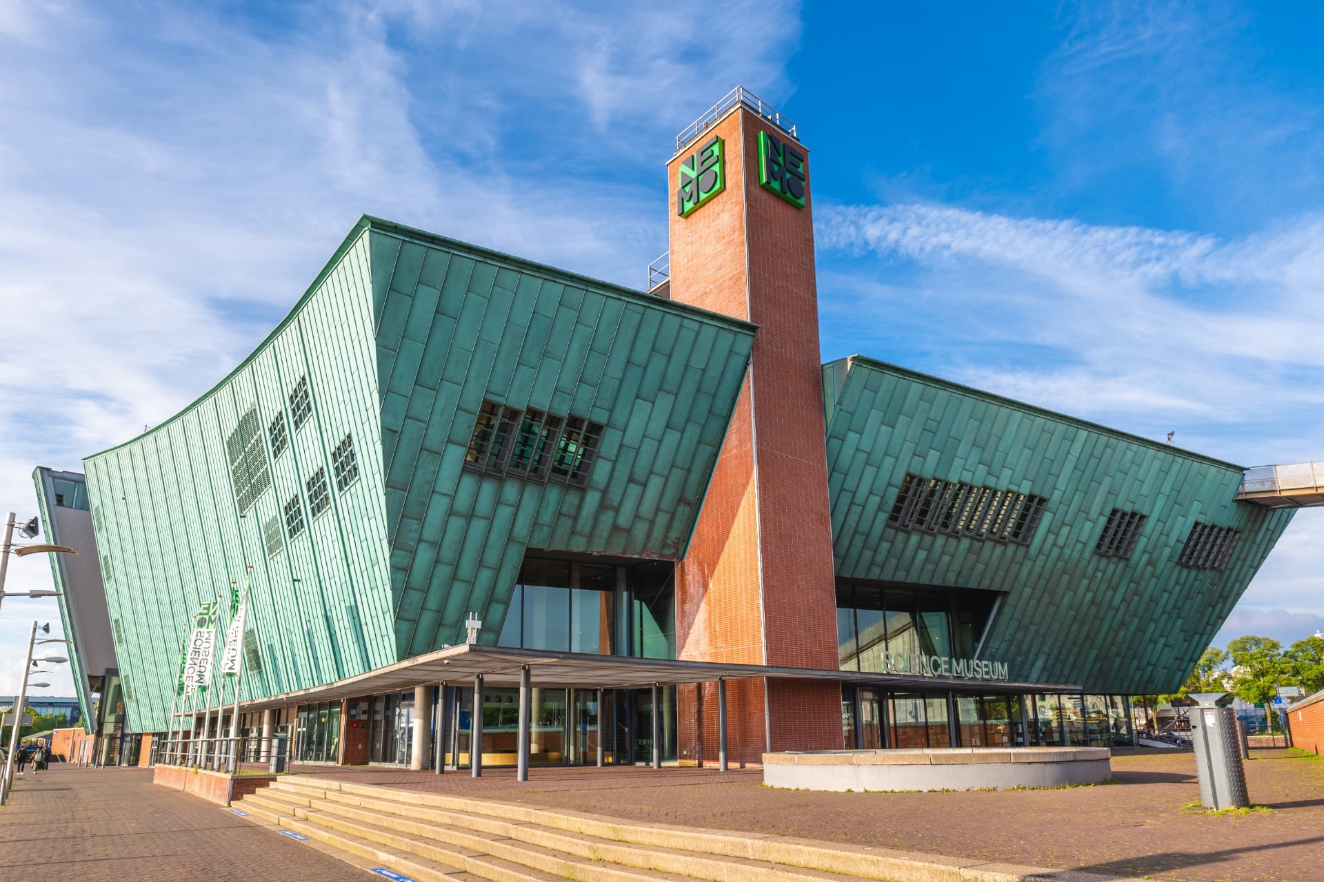 The green copper exterior and brick tower of the NEMO Science Museum in Amsterdam on a sunny day