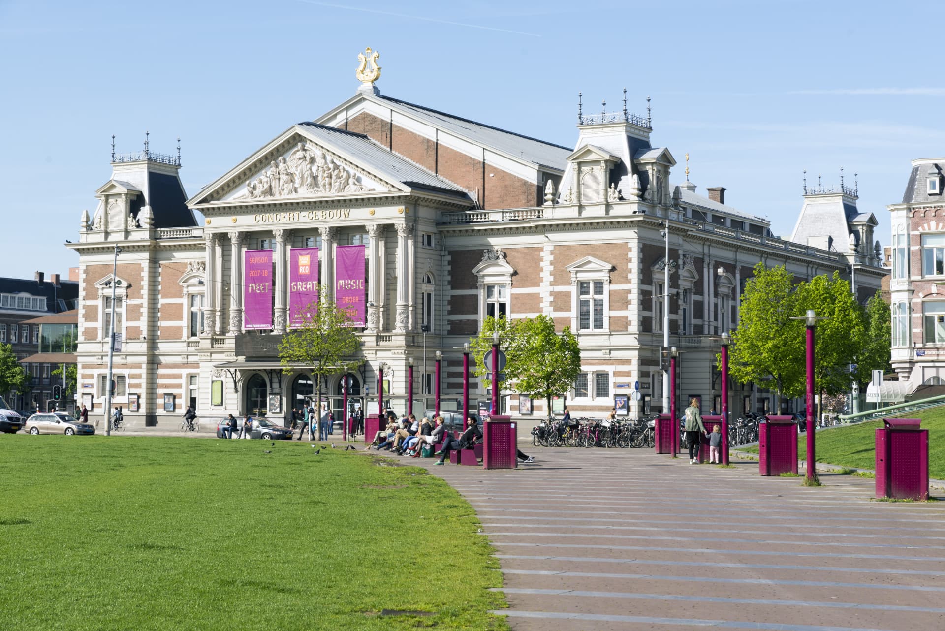 The Concertgebouw seen from the Museumplein lawn with people relaxing on benches in front
