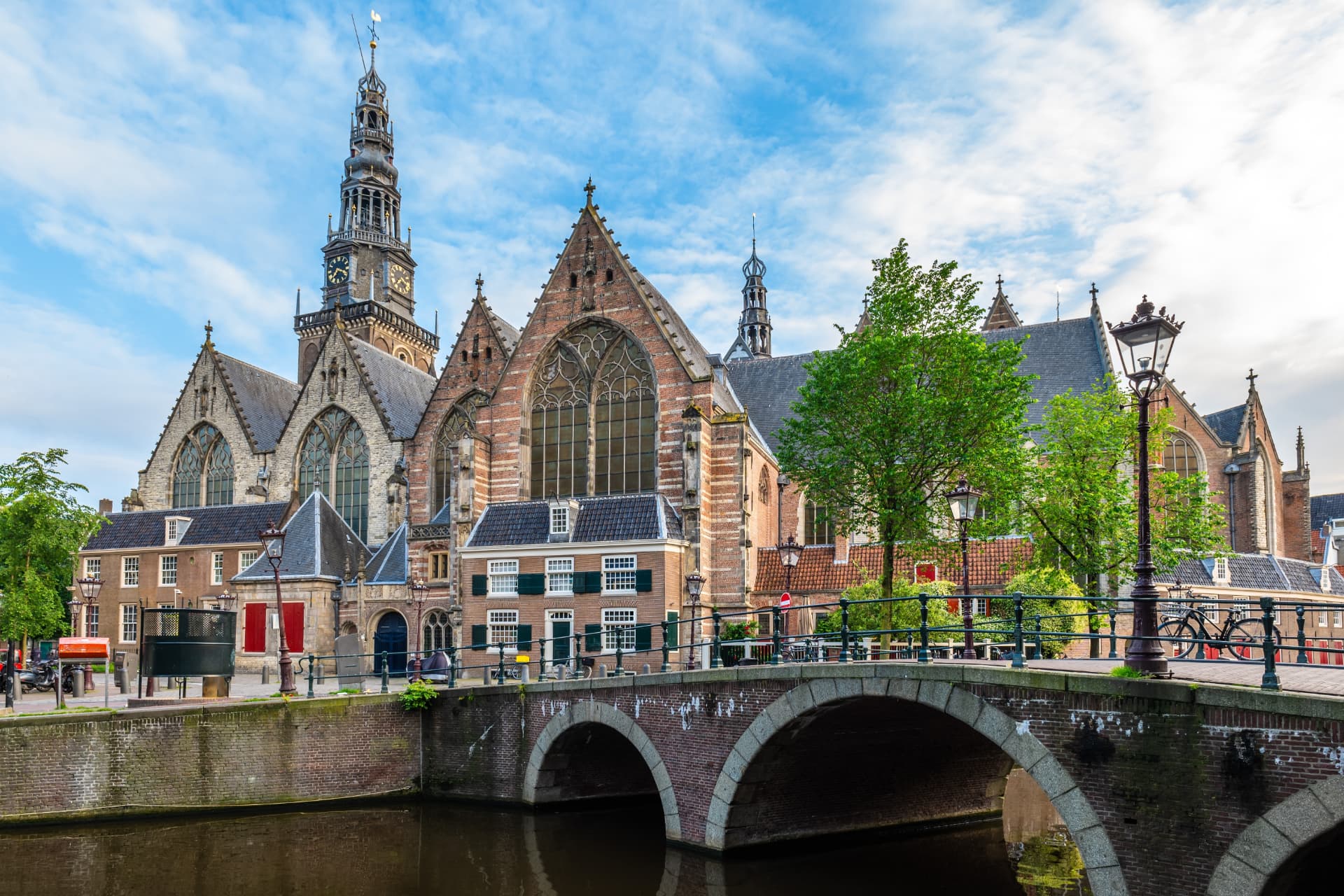 The Oude Kerk and its bell tower behind a canal bridge in Amsterdam
