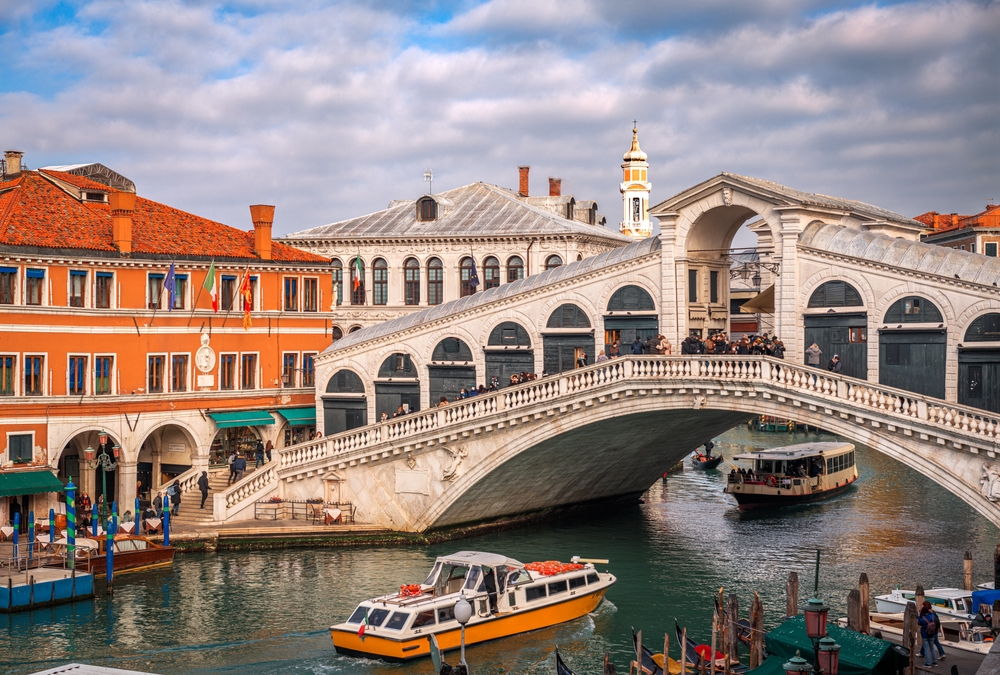 Le pont du Rialto au-dessus du Grand Canal à Venise avec des bateaux qui passent dessous
