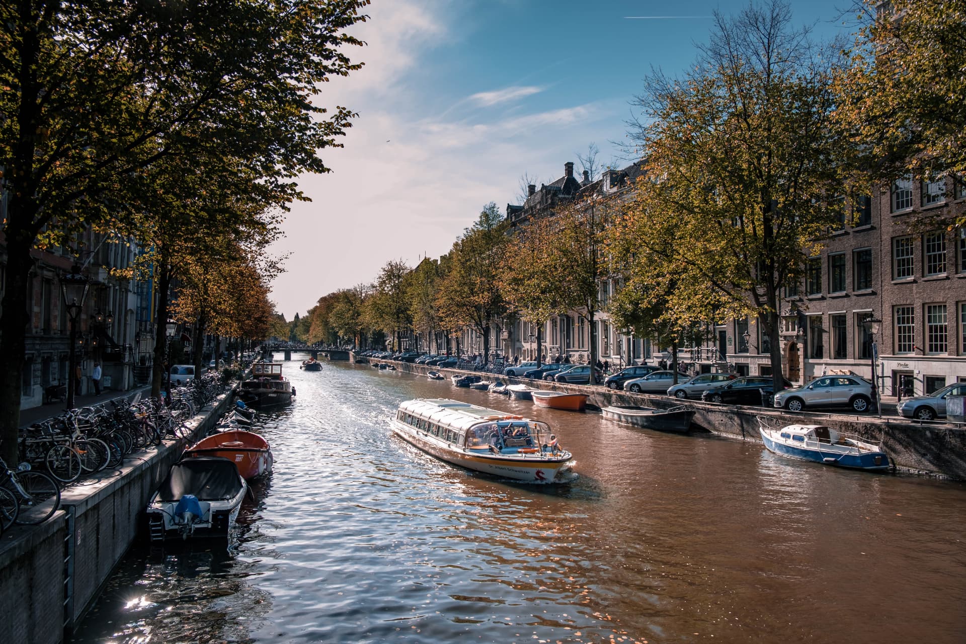 A tour boat on a tree-lined canal in Amsterdam's 9 Streets district