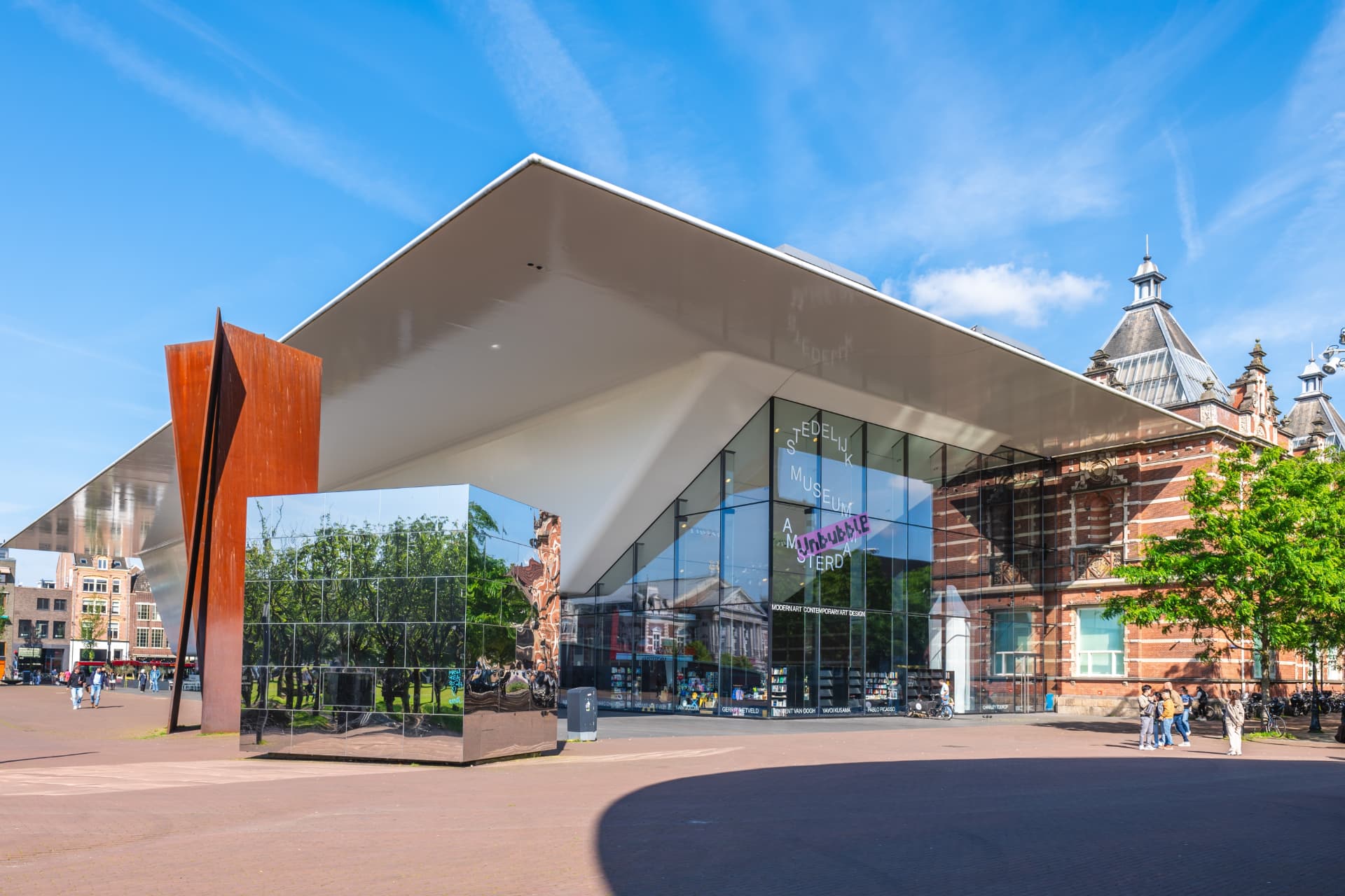 The glass entrance of the Stedelijk Museum under its white bathtub-shaped canopy