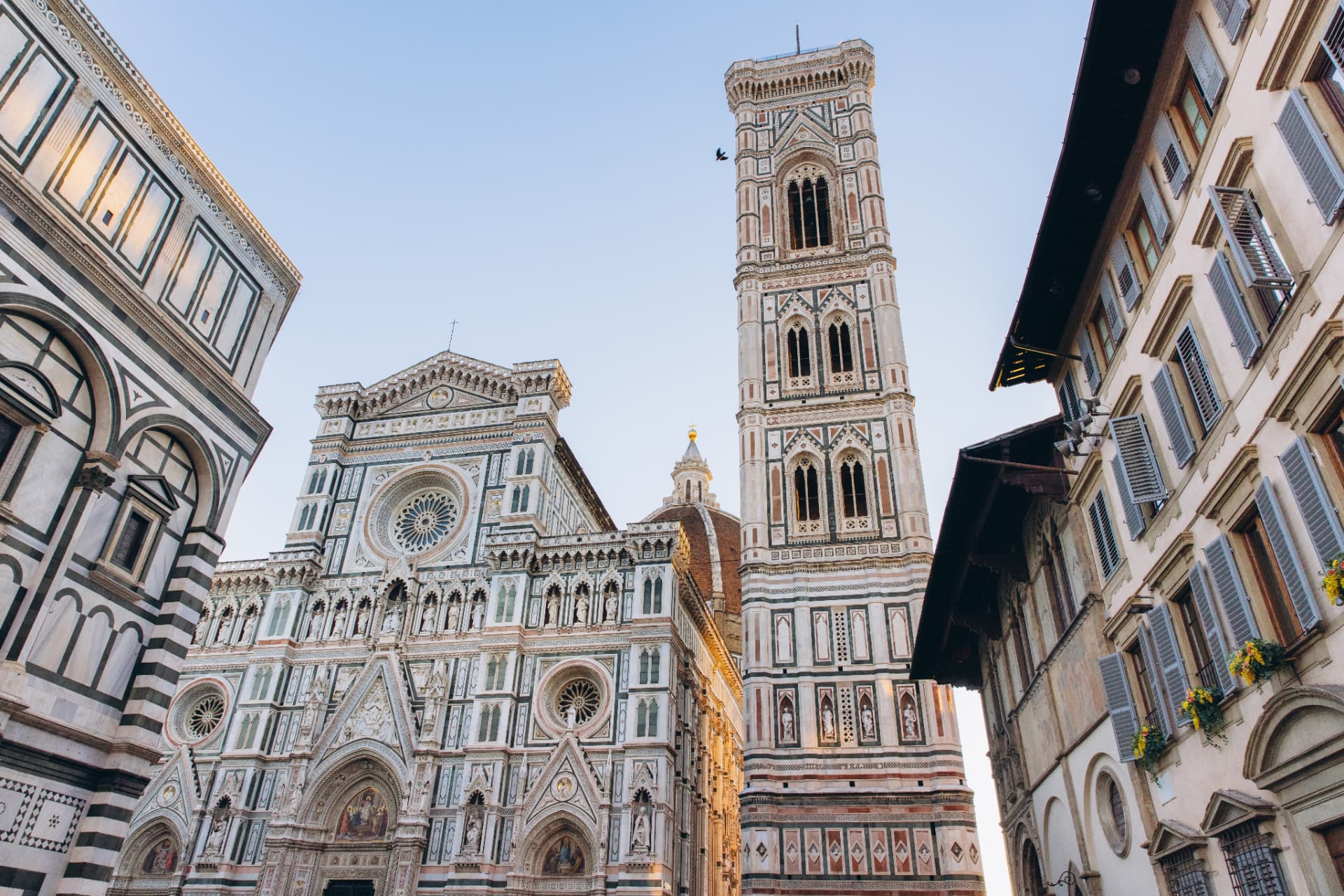 The marble facade of Florence Cathedral and Giotto's bell tower seen from street level in Piazza del Duomo