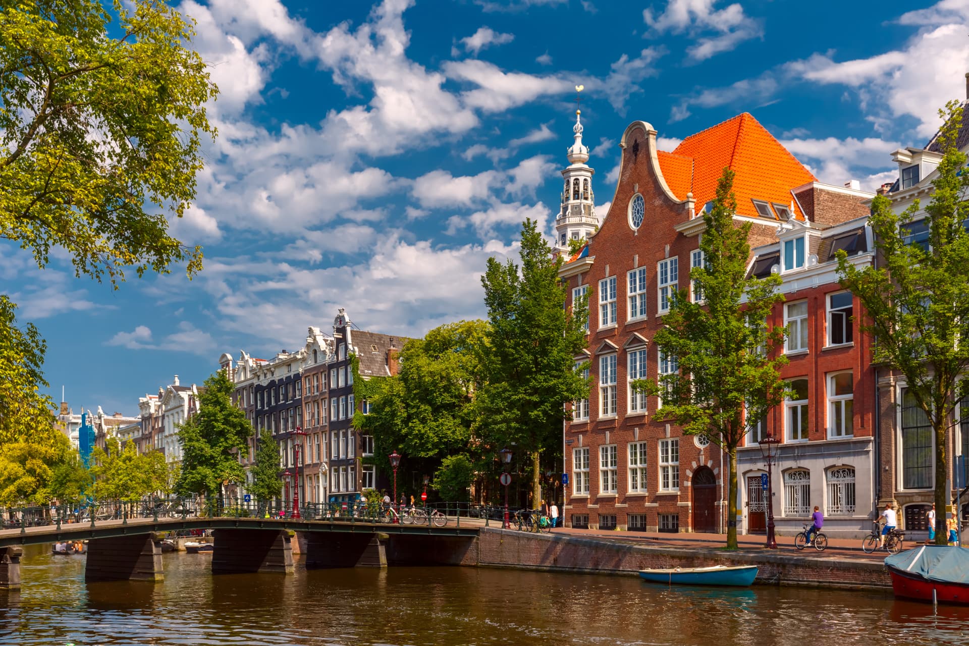 Bridge over an Amsterdam canal lined with gabled brick houses and bicycles