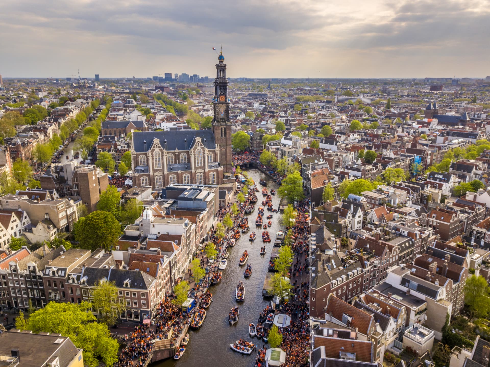 Aerial view of the Jordaan in Amsterdam with the Westerkerk and canals full of boats on King's Day