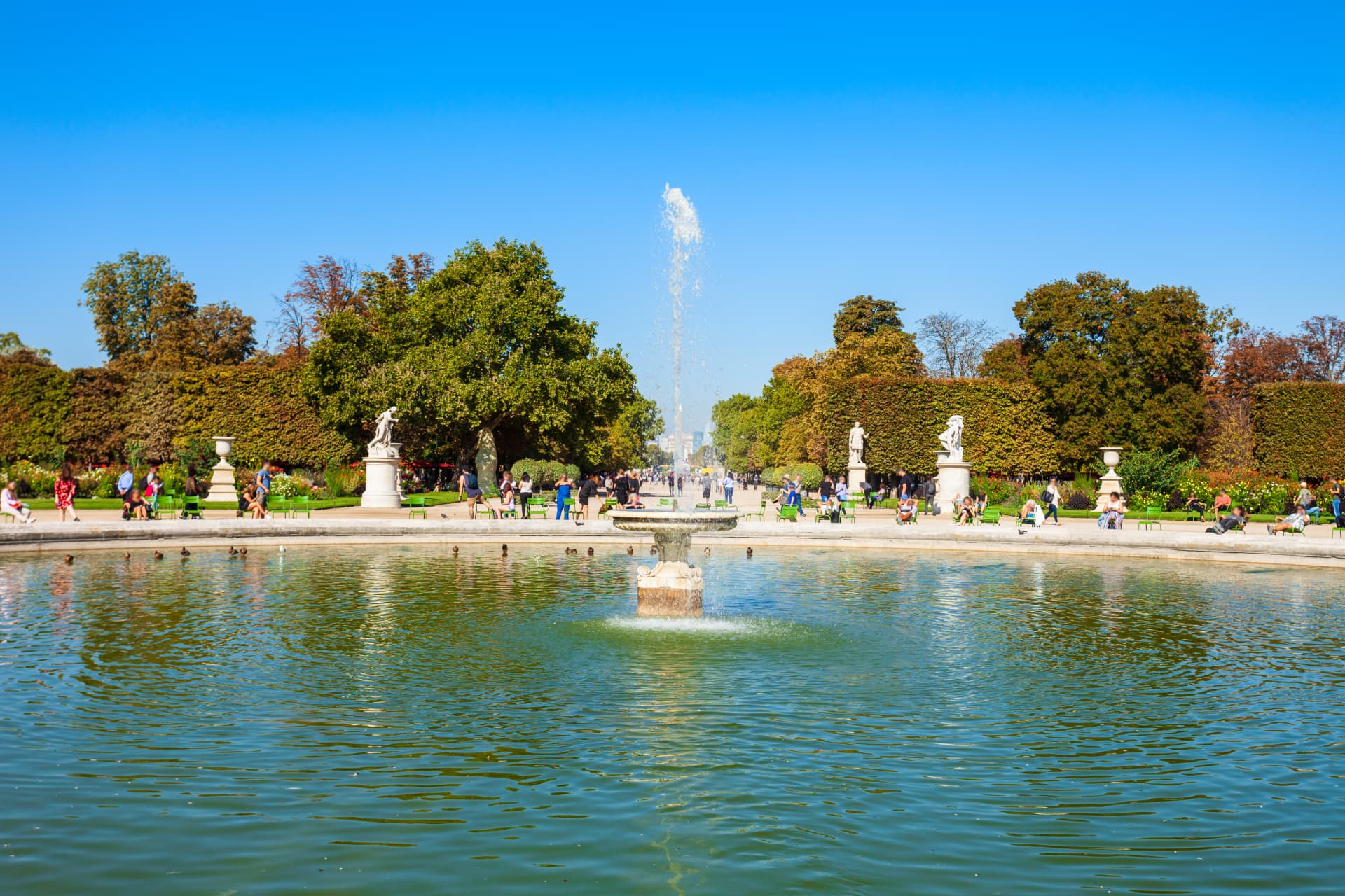Circular pond and central fountain in the Tuileries Garden with visitors and trees beyond