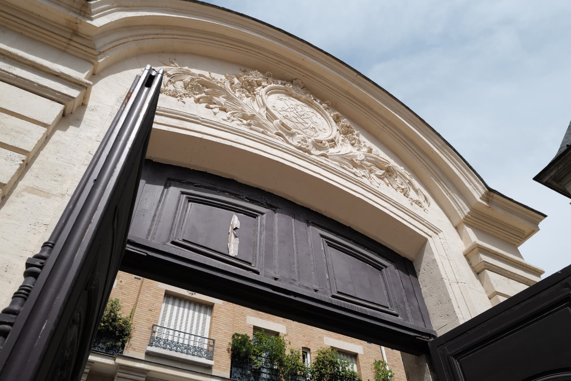 Carved stone archway with floral relief above an open dark wooden carriage gate