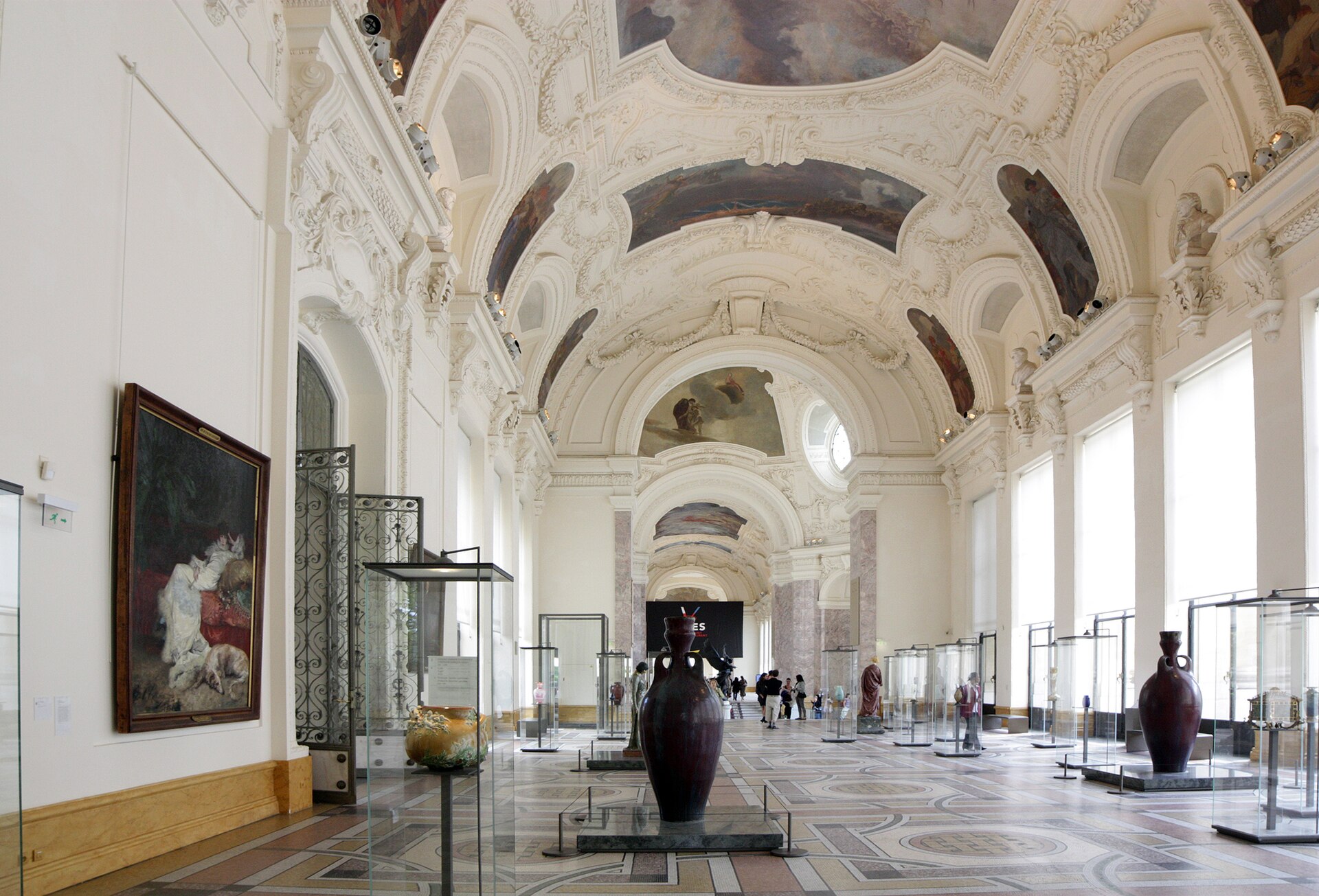 Vaulted exhibition gallery inside the Petit Palais with paintings, sculpture and display cases