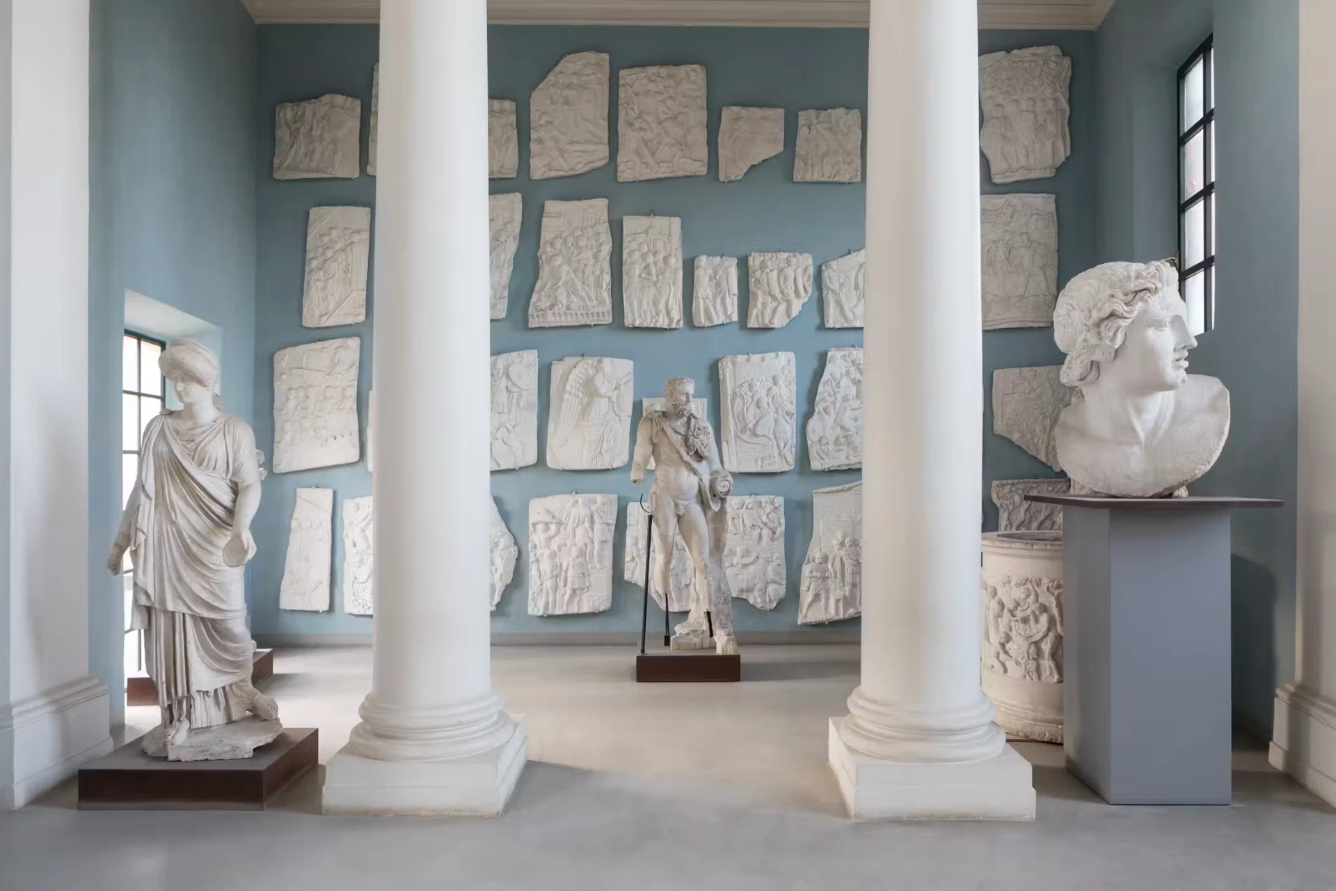 Plaster casts of reliefs and statues in a blue-walled gallery at Villa Medici