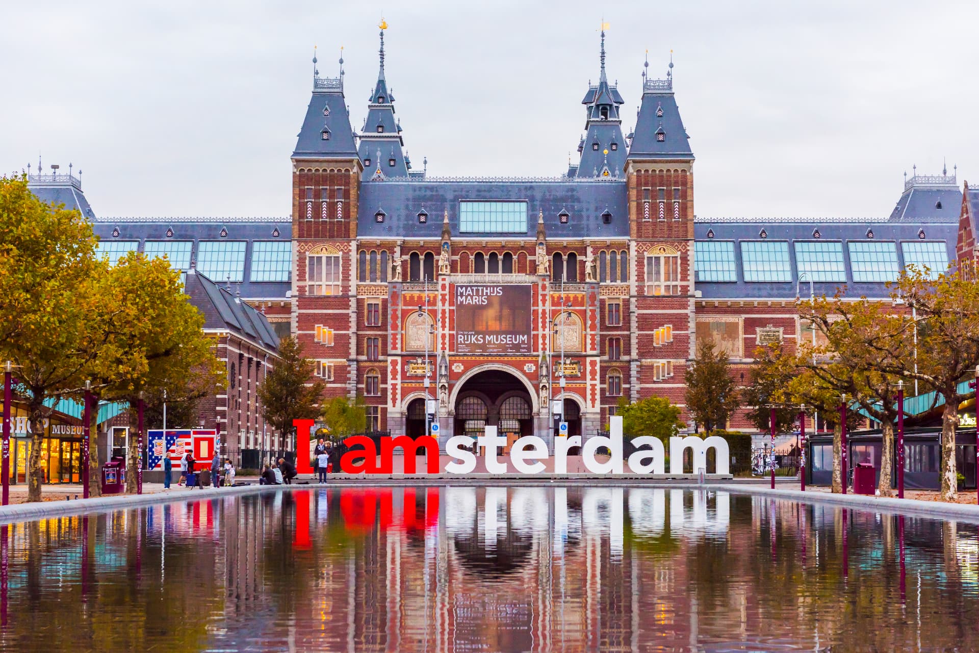 The Rijksmuseum facade behind the I Amsterdam sign, reflected in the Museumplein pond